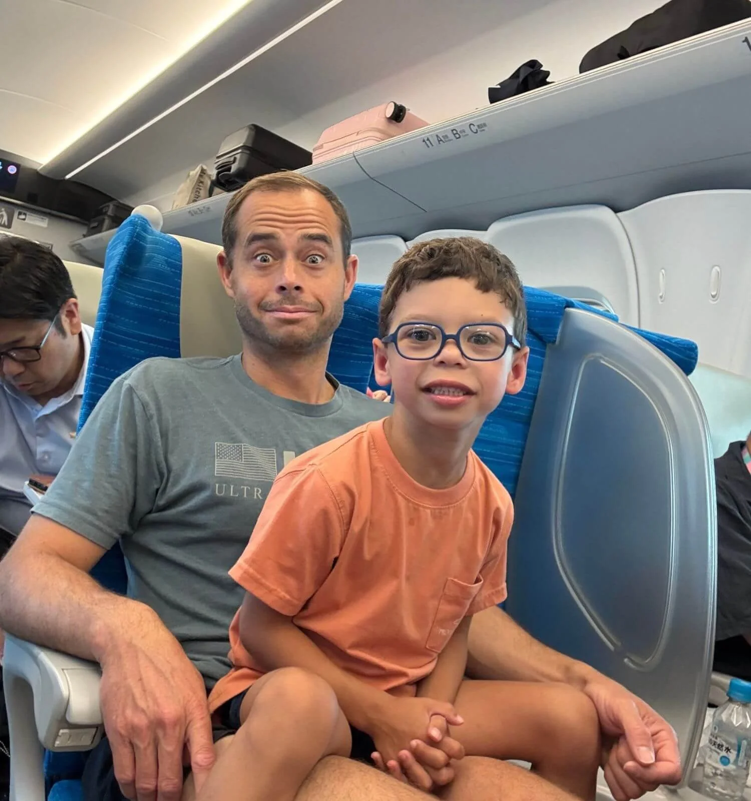 Young boy sitting on his father's lap aboard the Shinkansen bullet train in Japan