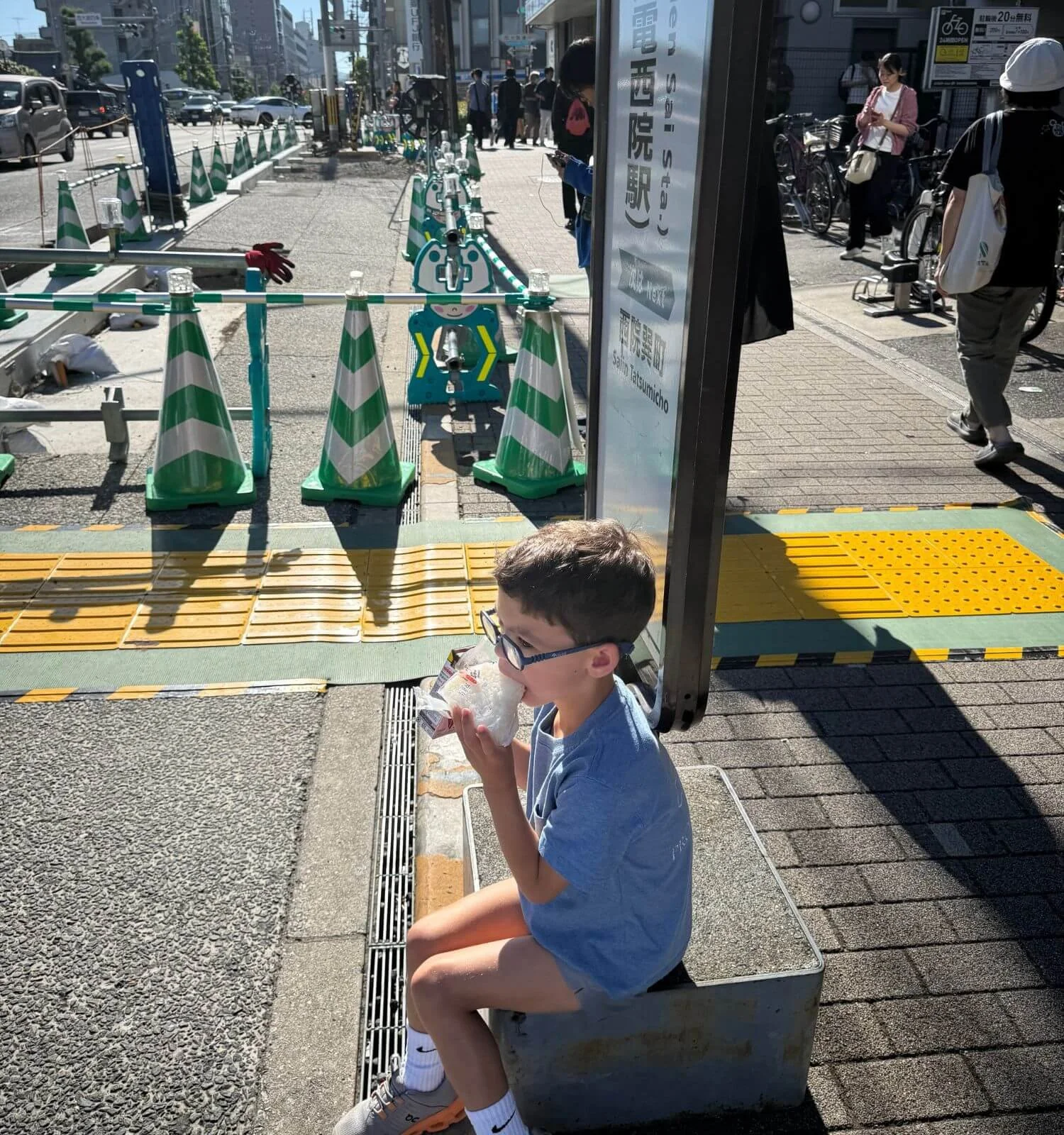 Boy eating a rice ball while waiting on a bus in Kyoto, Japan.