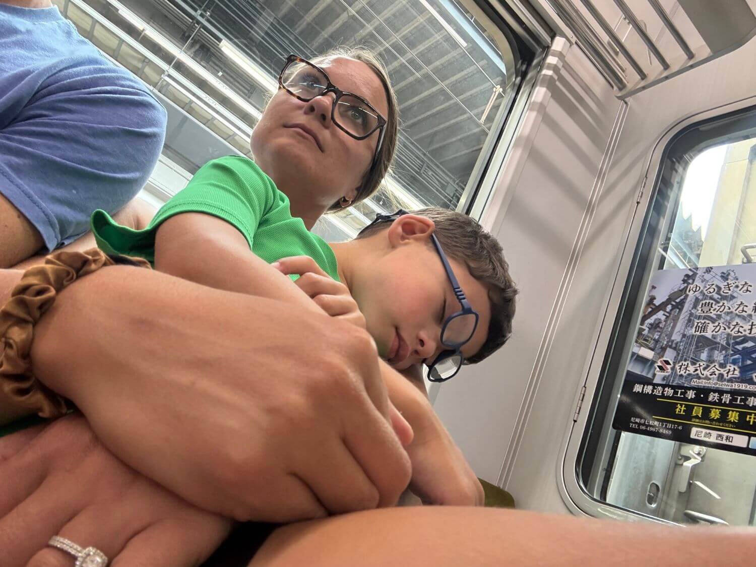 Boy napping on mom's lap on a Japan train.