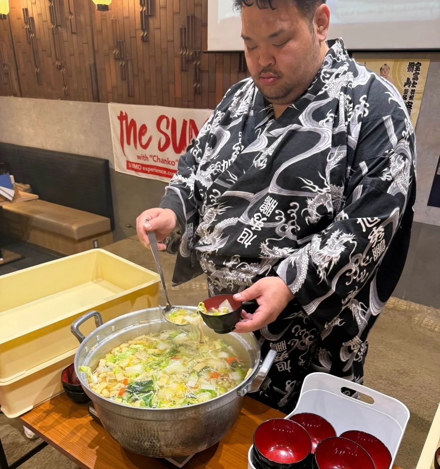 A sumo wrestler serving a traditional chanko lunch at a sumo show in Tokyo, Japan.