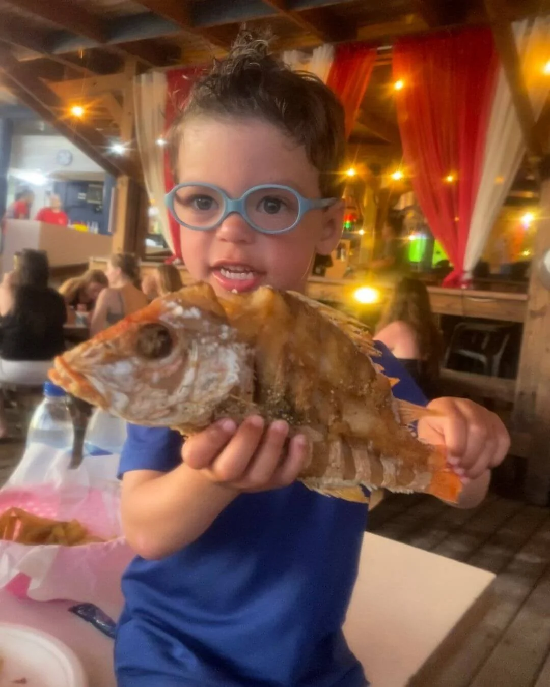 Child holding fish at Zeerovers in Aruba during family trip.