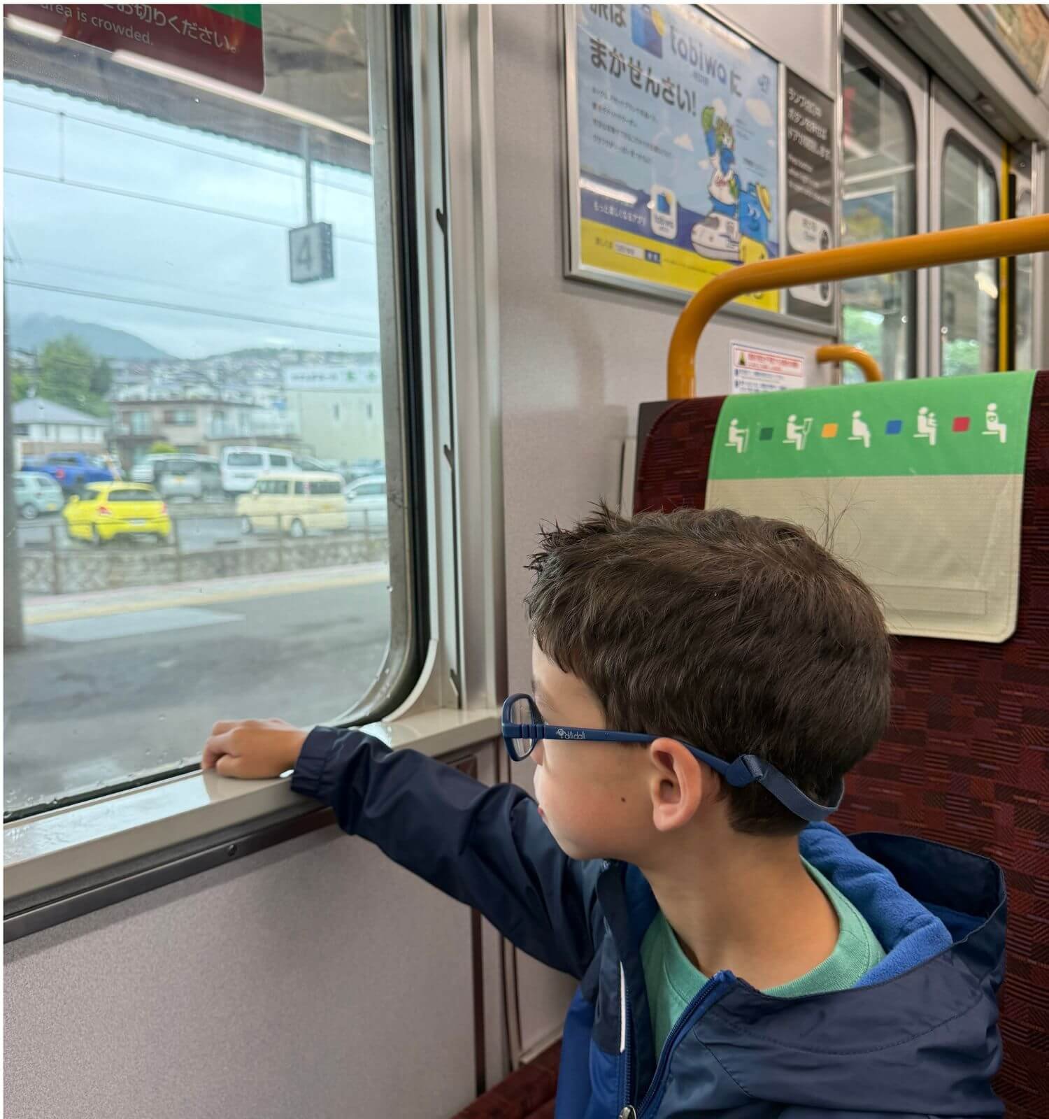 Young boy sitting quietly looking out the window of a bus in Japan