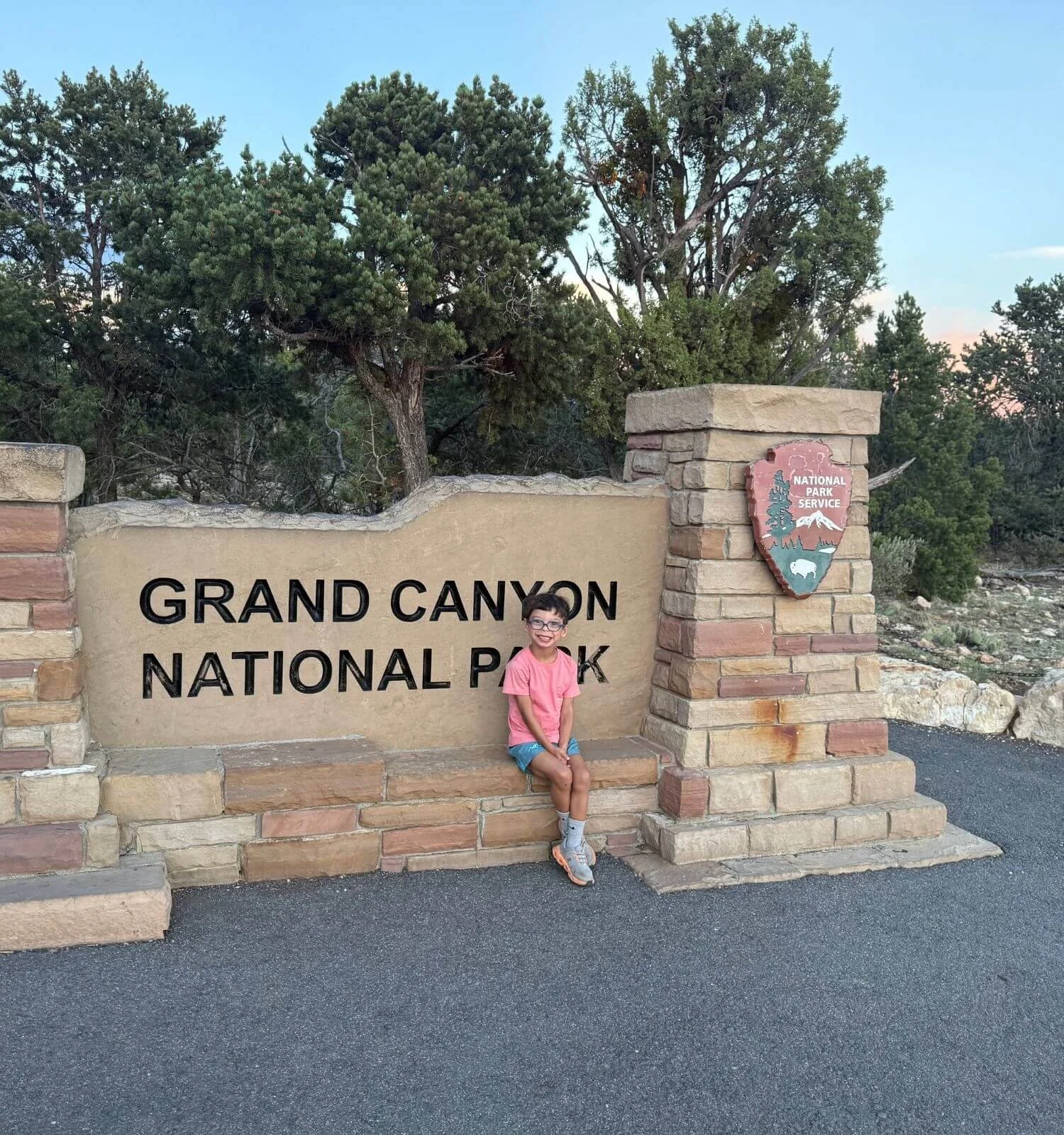 Smiling boy standing in front of the Grand Canyon National Park sign at Mather Point.