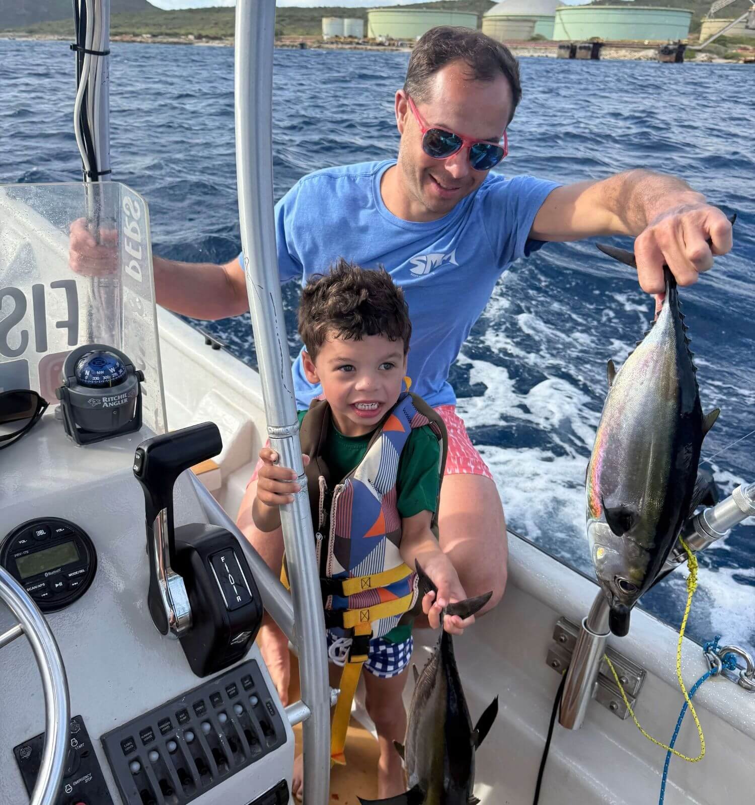 Boy holding a tuna with his dad caught on a fishing charter in Bonaire.
