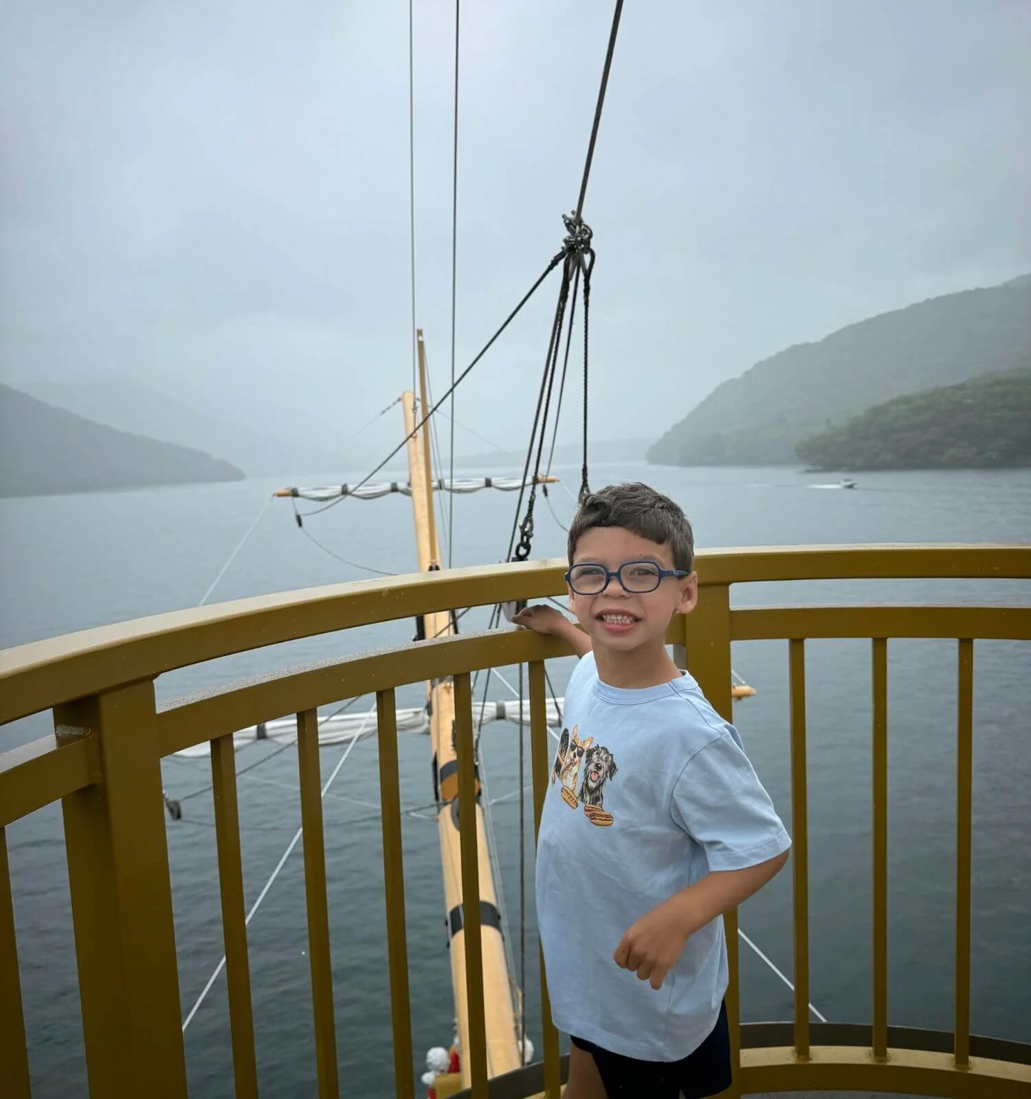 A young boy smiling in the crow's nest of the Hakone pirate ship on Lake Ashi, Japan.
