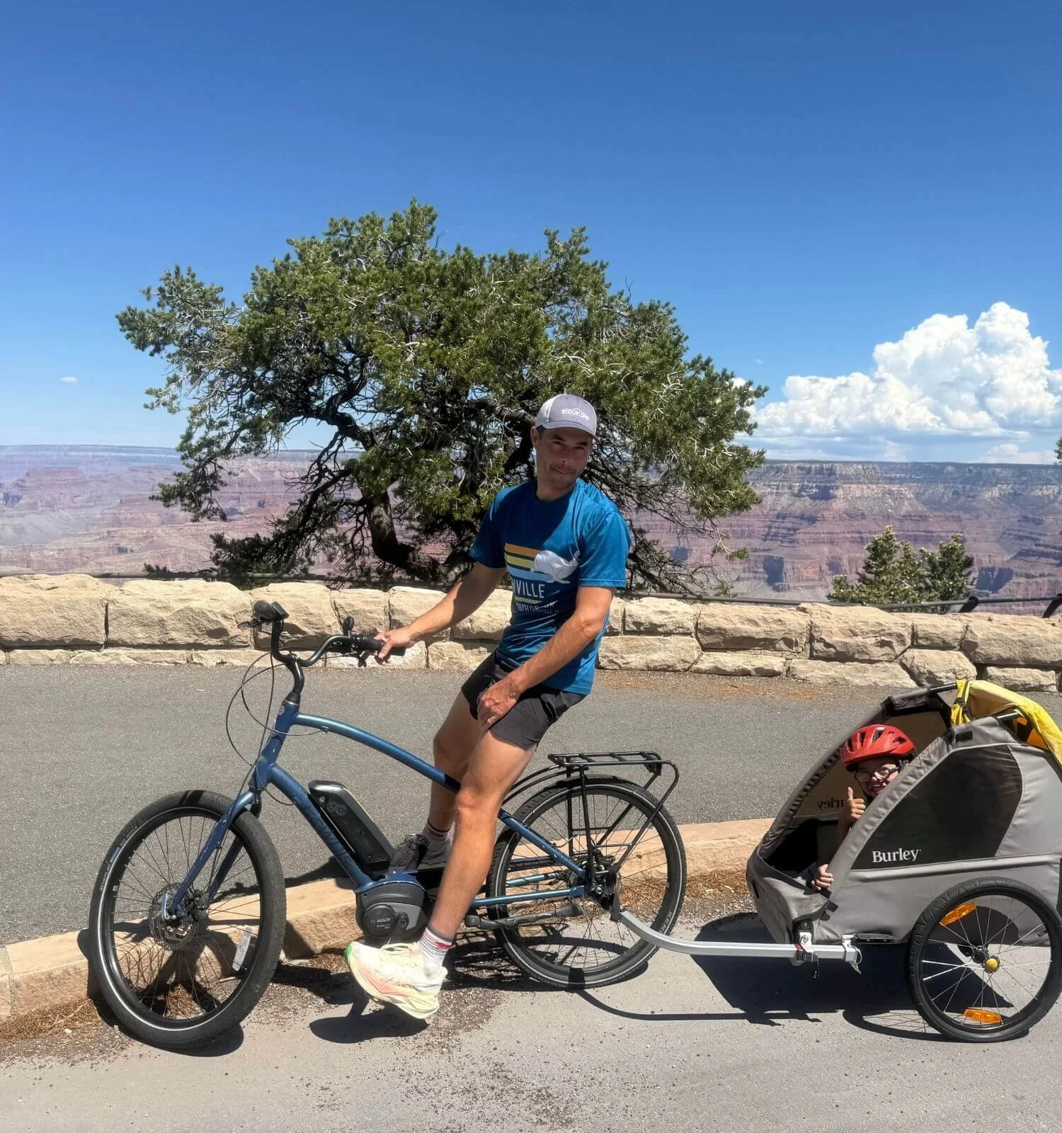 Dad riding a bike with a bike trailer carrying his son in the Grand Canyon National Park Hermit's Road.