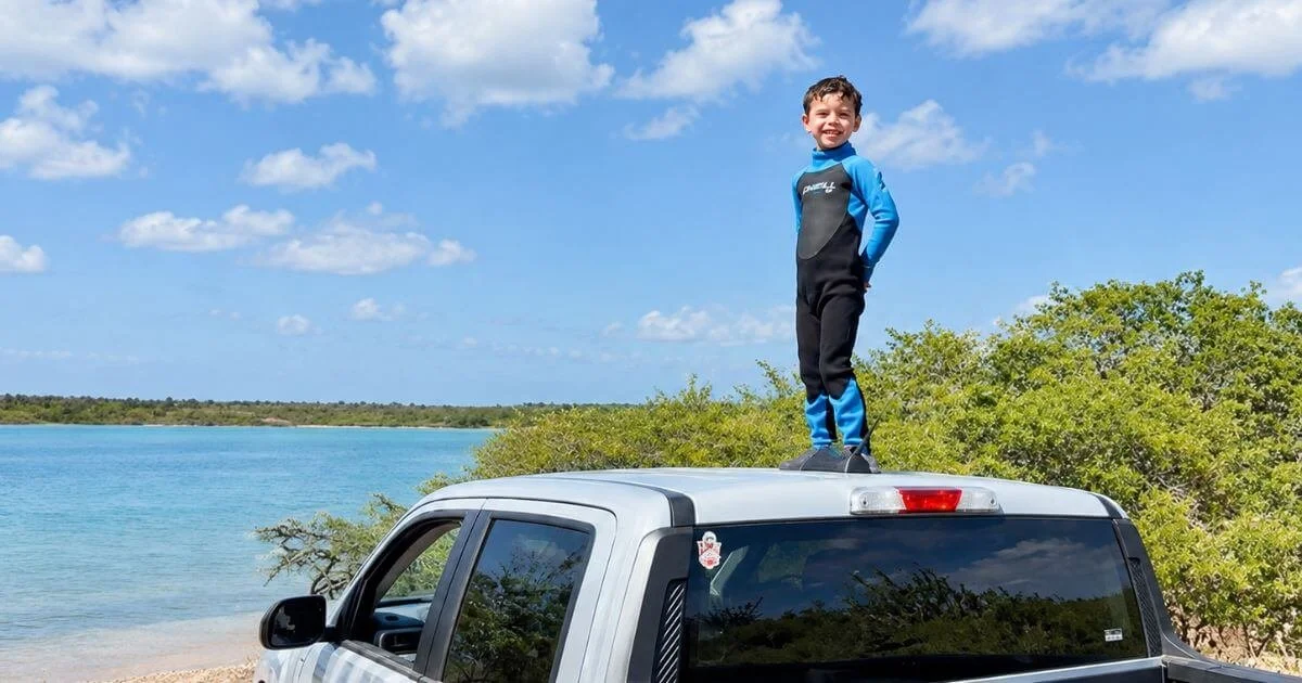 Boy standing in the back of a rental truck watching flamingos in Washington-Slagbaai National Park, Bonaire.