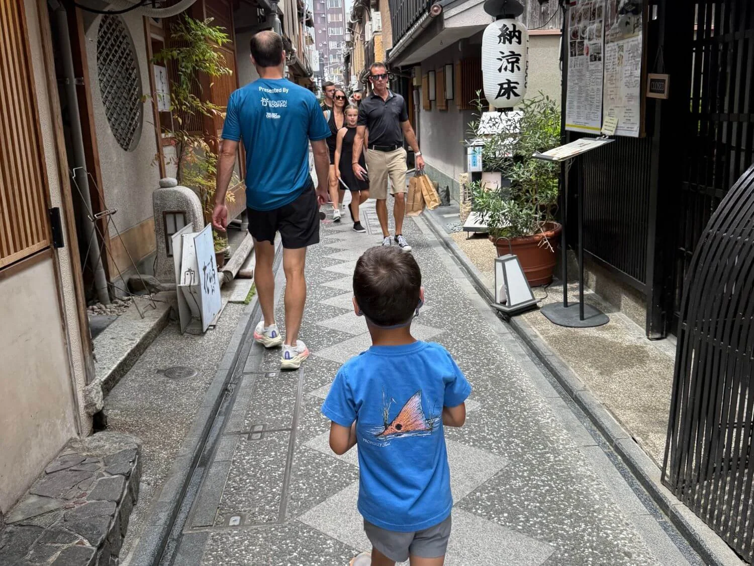 Boy walking with his dad on a street in Kyoto, Japan.