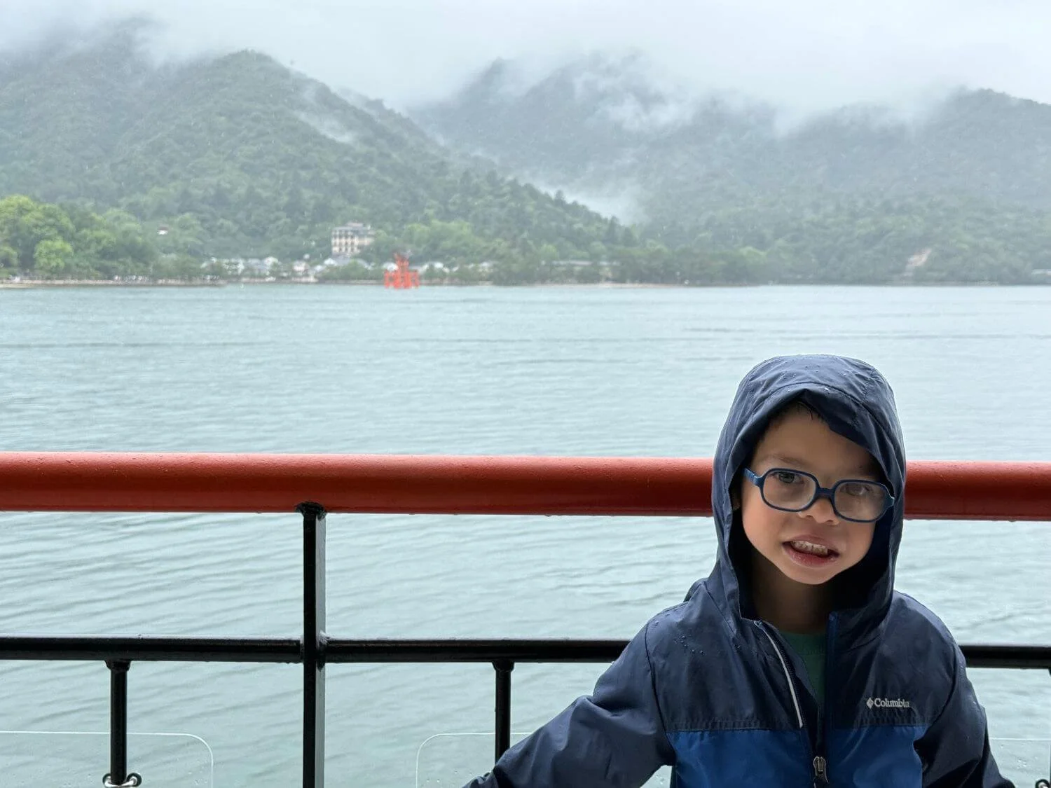 Boy in rain gear on a ferry from Miyajima to Hiroshima during an incoming typhoon.