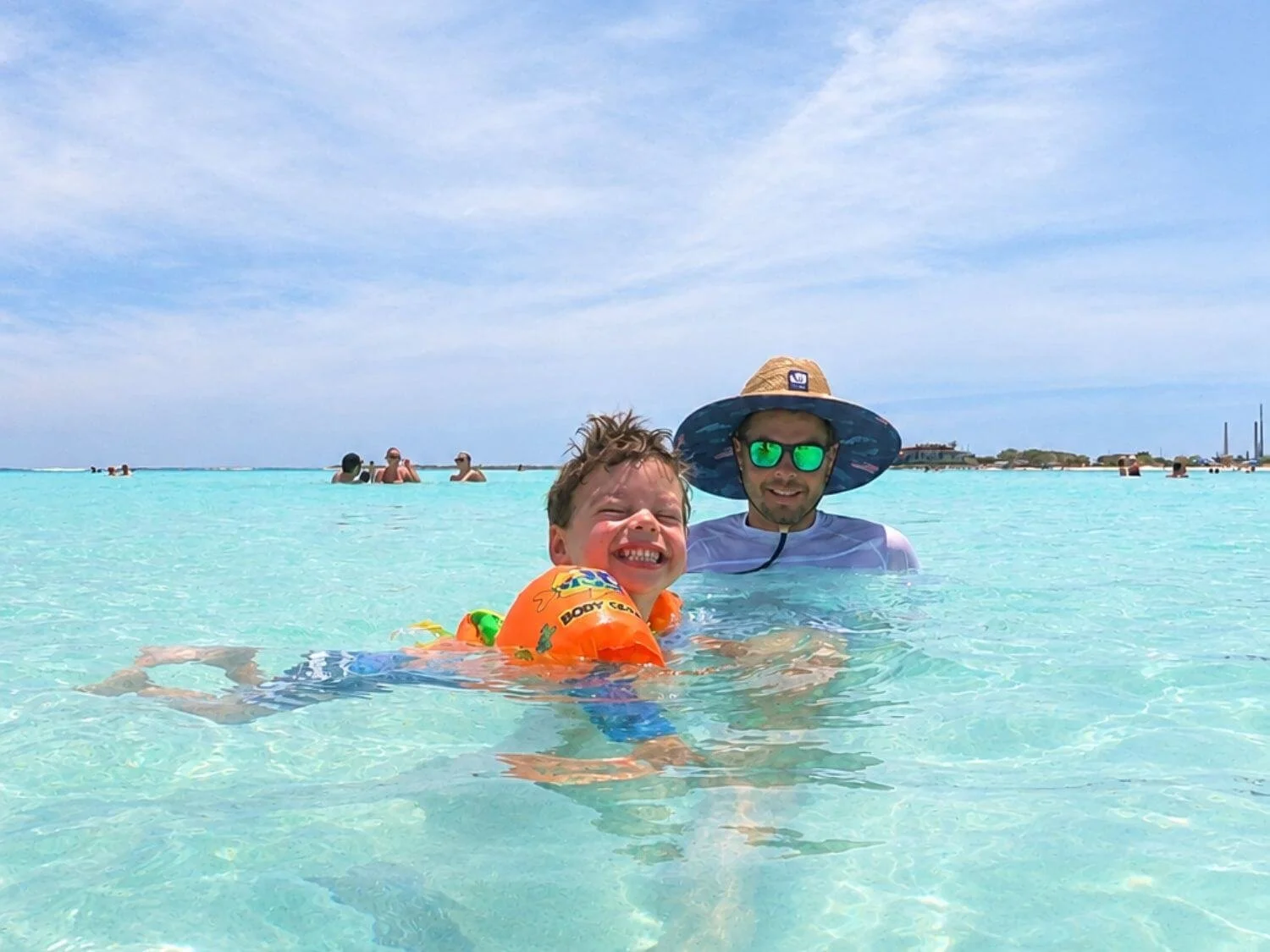 Father and son swimming in the calm, shallow water at Baby Beach in Aruba.