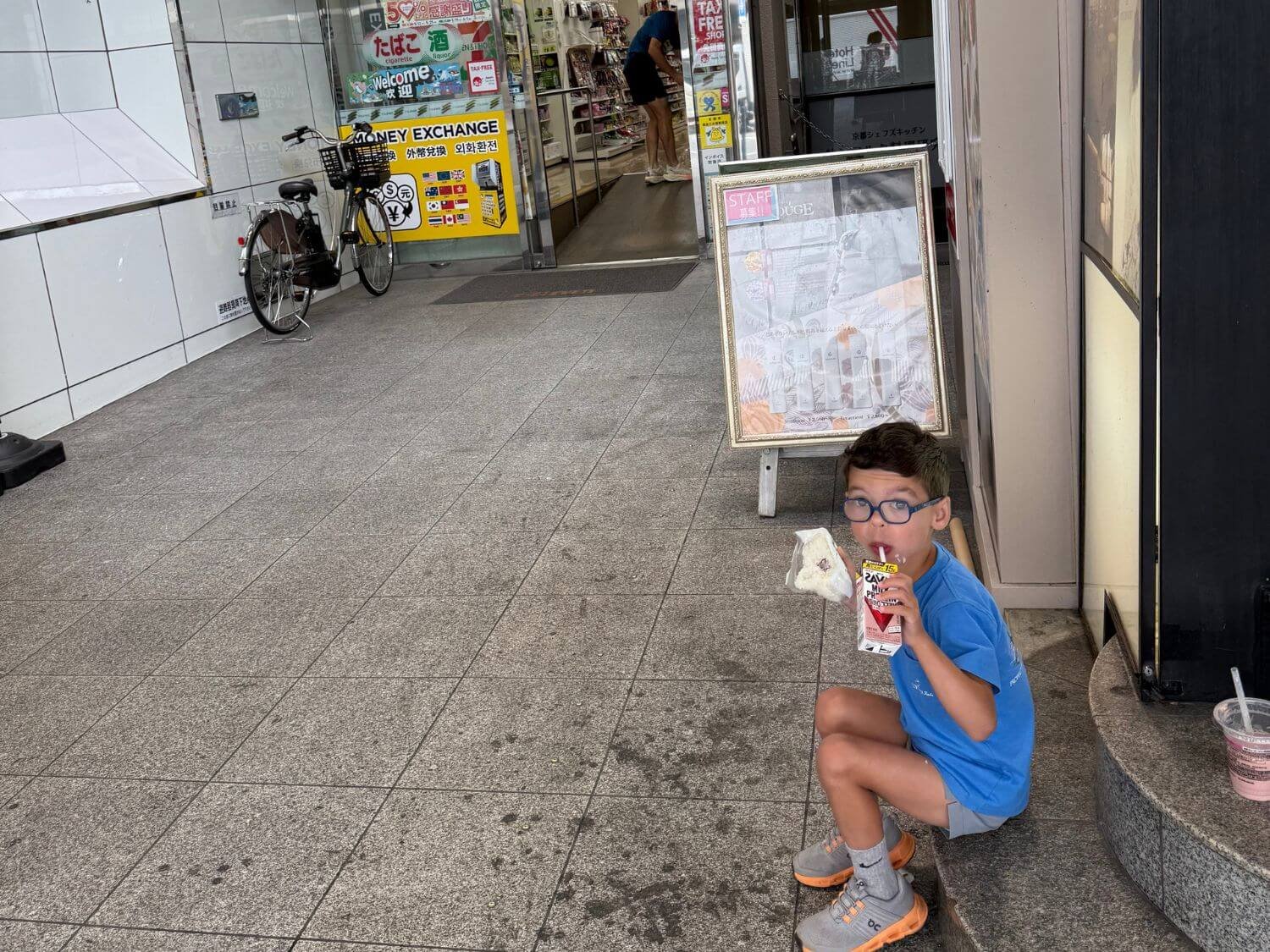 Boy eating breakfast outside a 7-Eleven in Kyoto, Japan