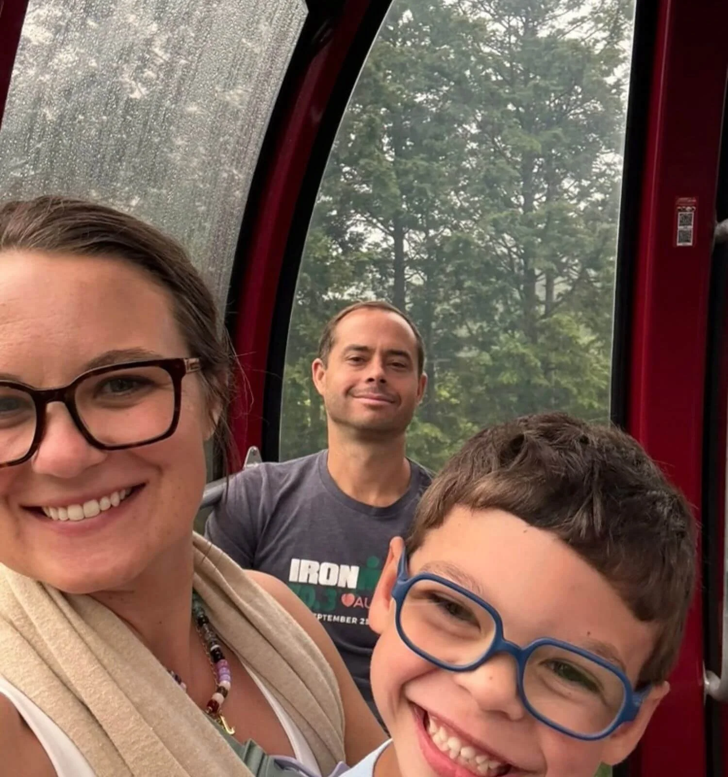 Family smiling during a selfie on the ropeway portion of the Hakone Loop in Japan.