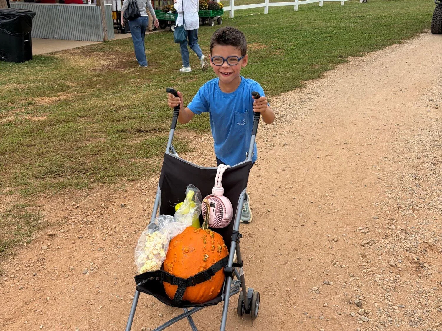Boy pushing a pumpkin in a stroller at Denver Downs in Anderson, South Carolina.