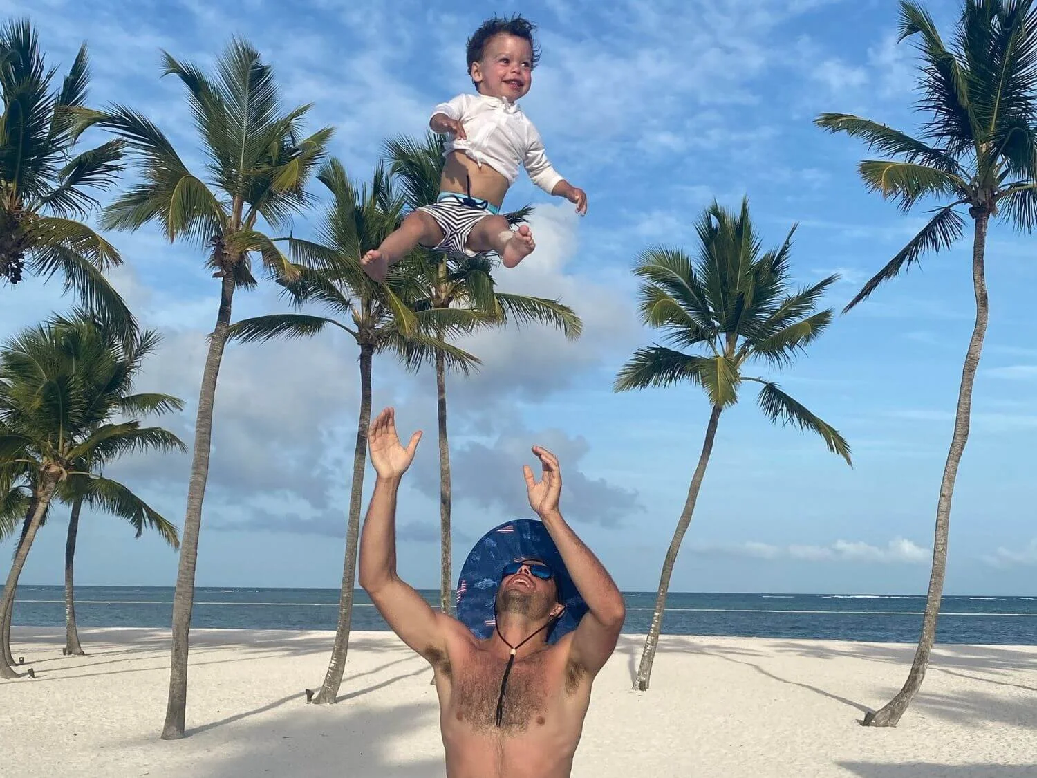 Father tossing his toddler up on the beach in the Dominican Republic.