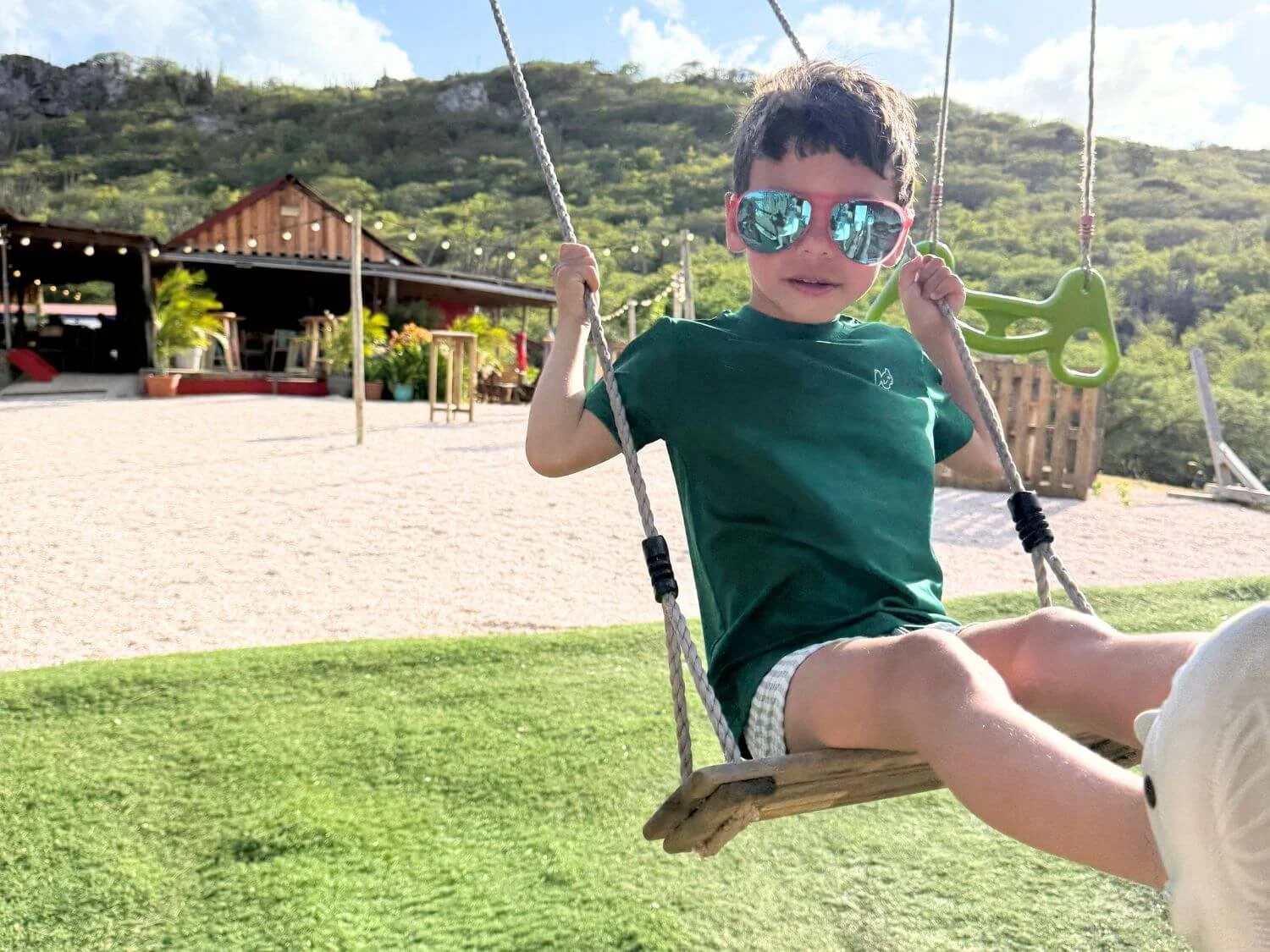 Boy in sunglasses swinging at Posada Para Mira in Bonaire.