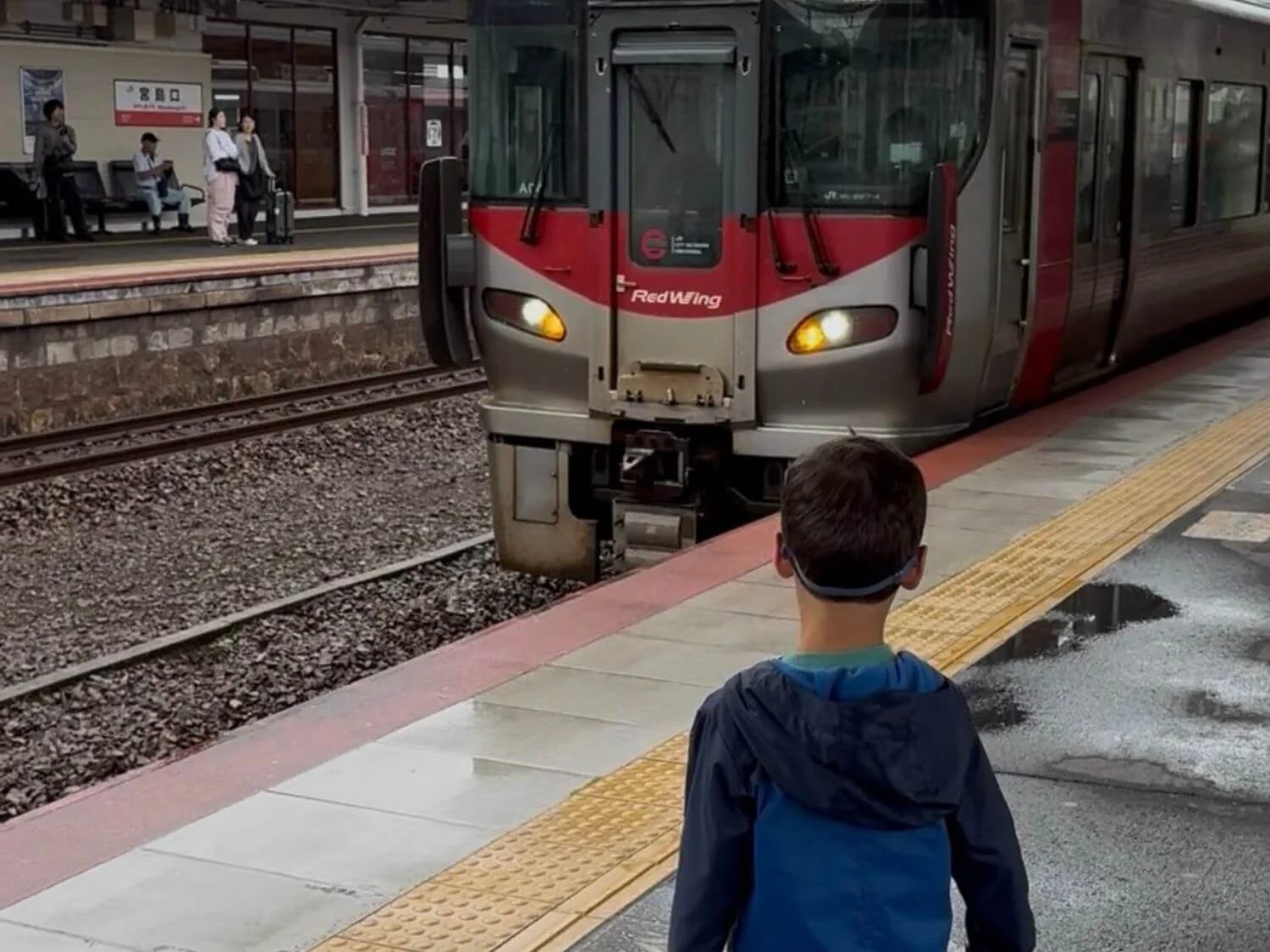 Boy waiting on a train platform as train approaches in Hiroshima, Japan.