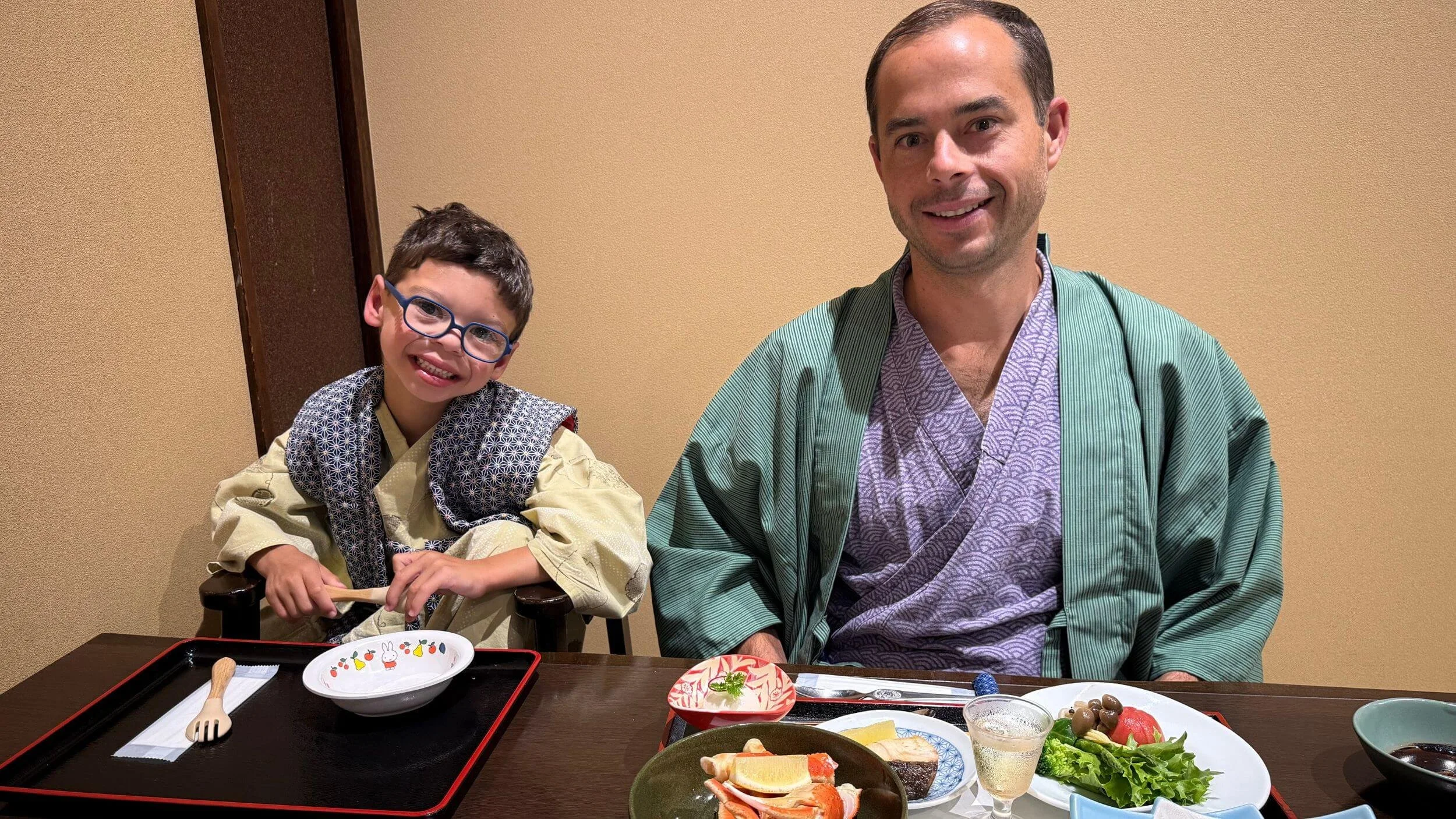 Father and son in yukata robes eating a traditional kaiseki dinner at a ryokan in Hakone, Japan