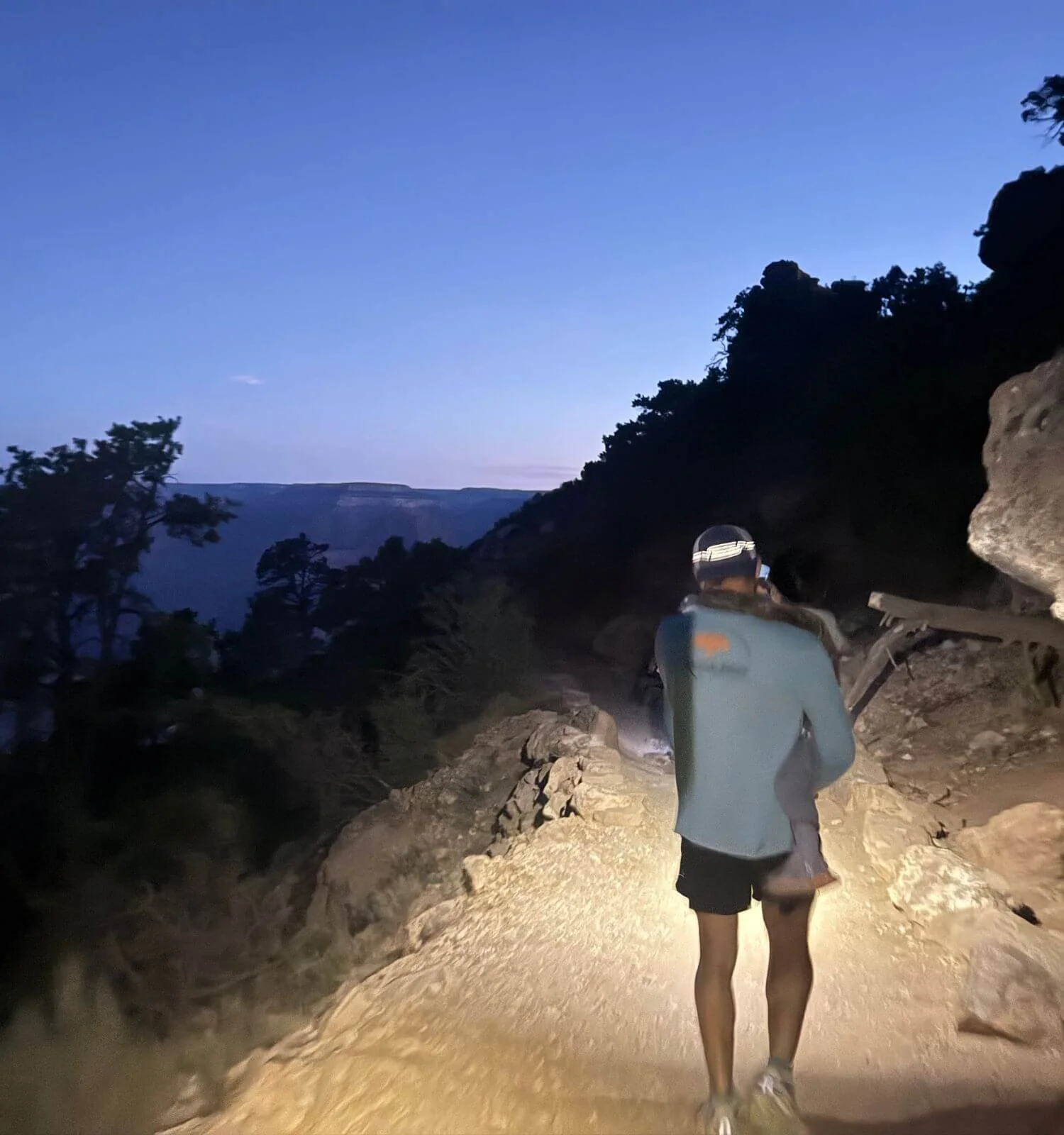 Father carrying son down South Kaibab trail to Ooh Aah Point before sunrise in the Grand Canyon National Park in Arizona, USA