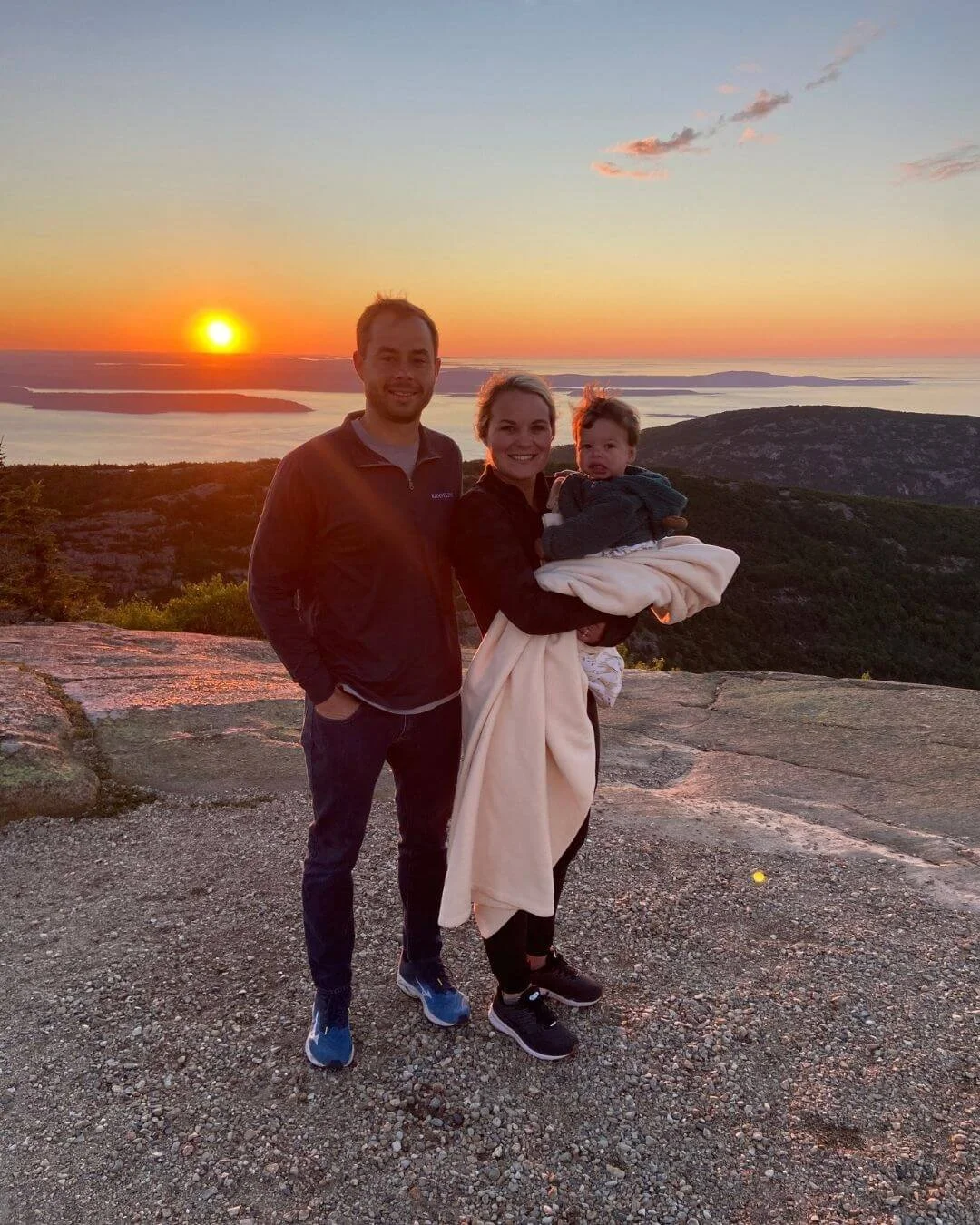 Family on Cadillac mountain viewing sun come up in Acadia National Park.