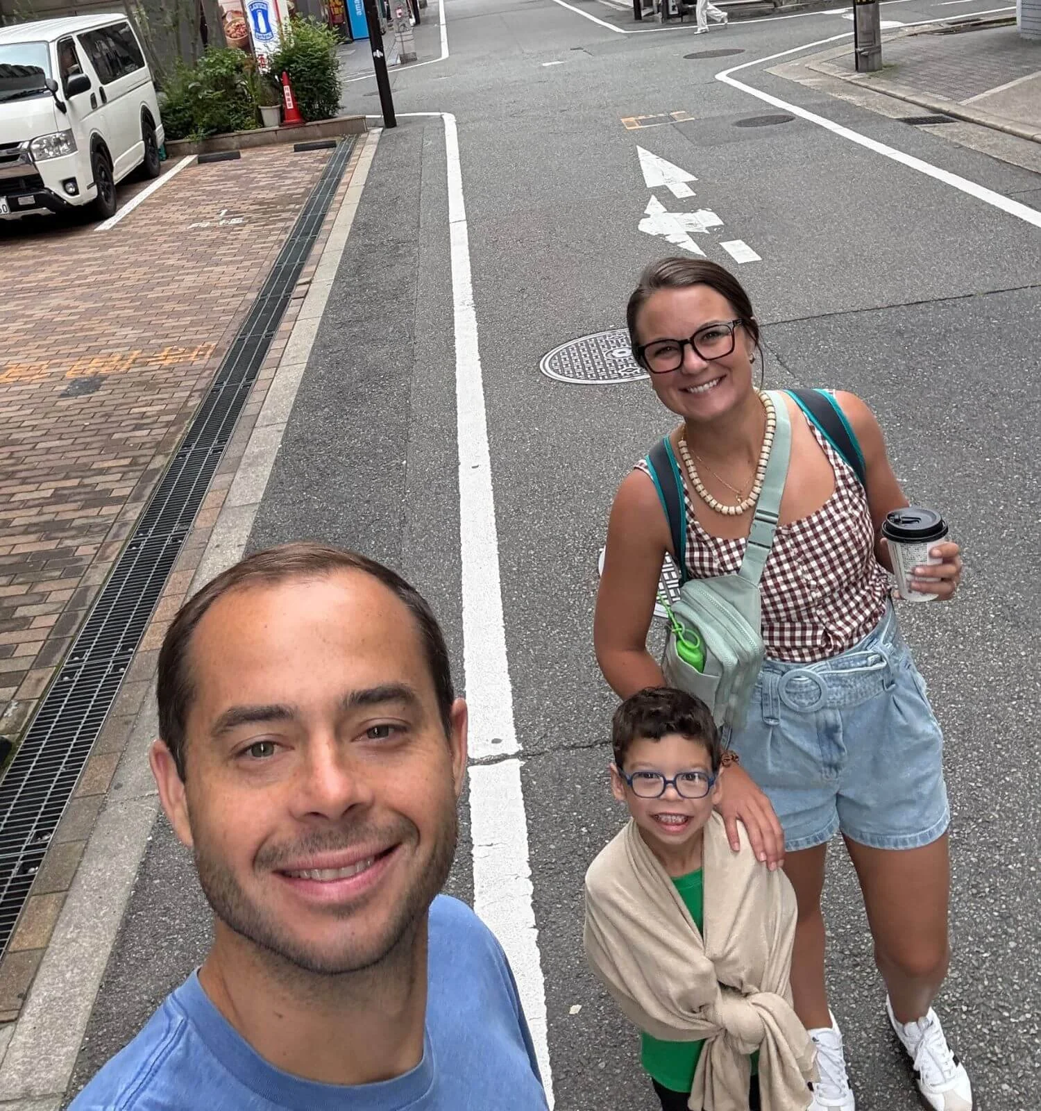 Young boy wrapped in a beige travel shawl while standing on a street in Japan