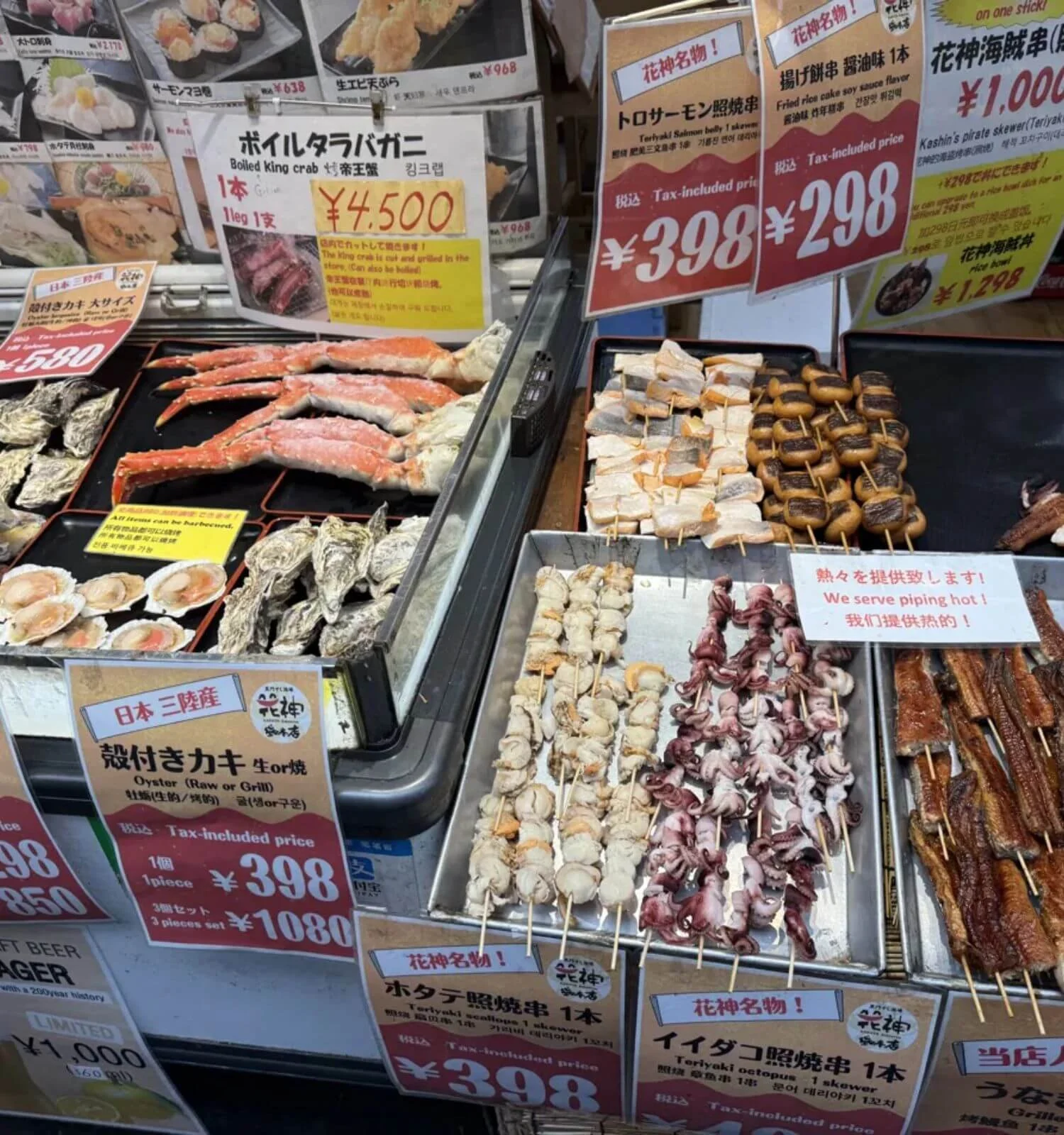 Grilled seafood skewers and crab legs displayed with pricing signs at Kuromon Market in Osaka, Japan
