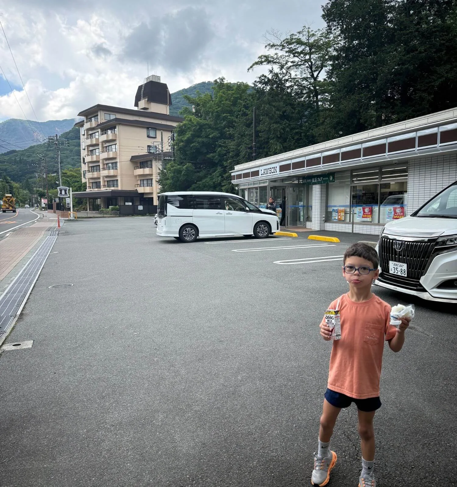 Young boy holding a rice ball and chocolate milk purchased at a Lawson convenience store in Hakone, Japan