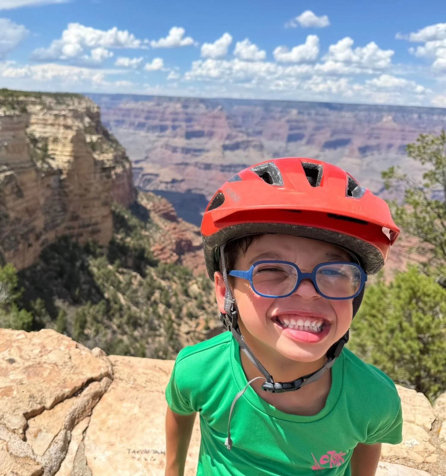 Boy smiling at the grand canyon while wearing his bike helmet from a family bike ride on hermit's road .
