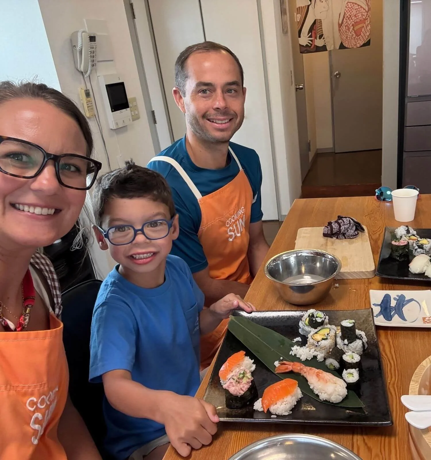 A family of three taking a selfie during a gluten-free sushi-making class in Tokyo, Japan.