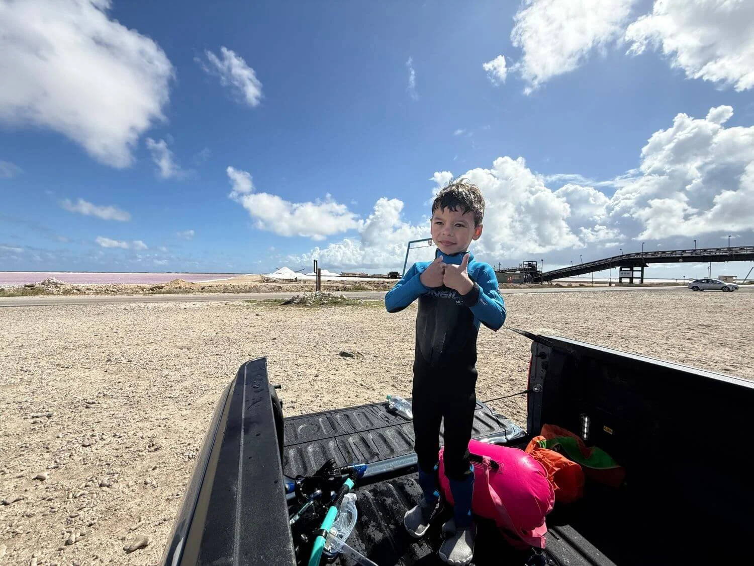 Boy in the back of a truck in front of salt mountains in Bonaire.