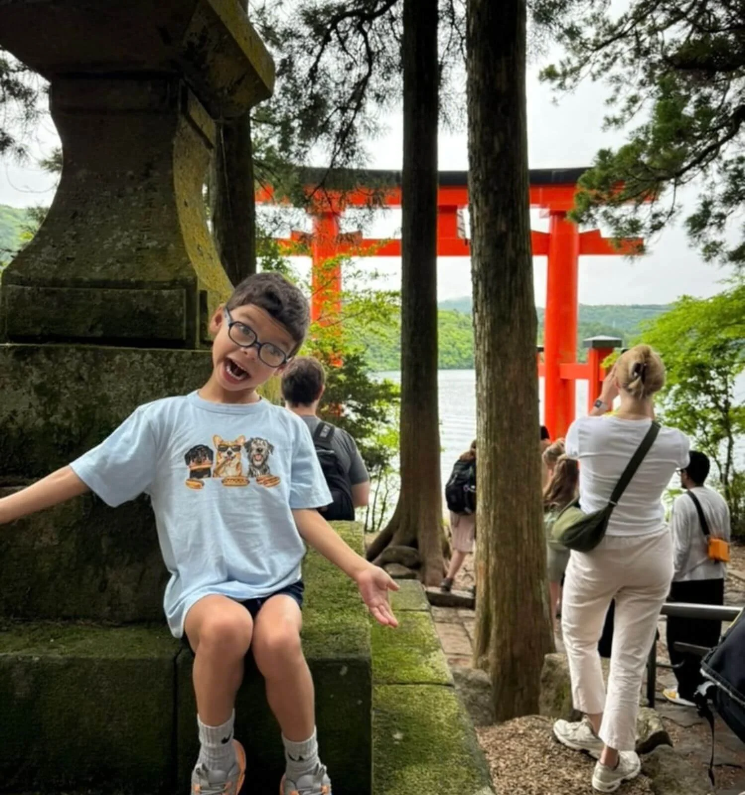 Boy being silly in front of the floating torii gate in Hakone Japan.