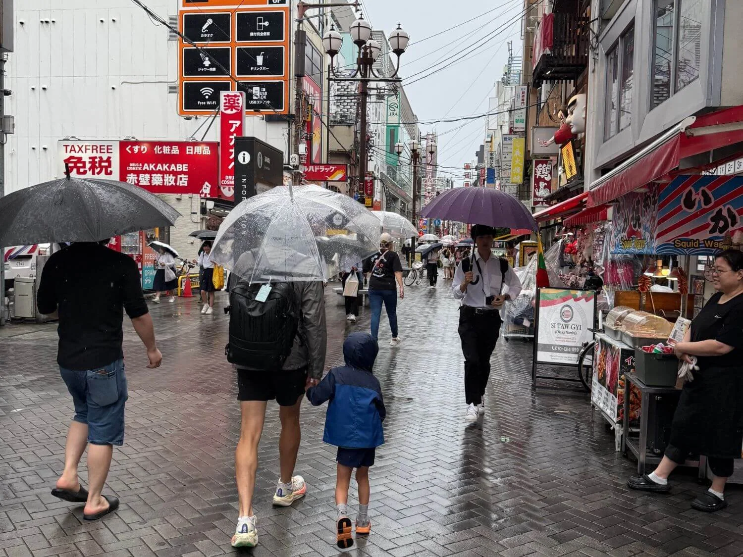 Father and son walking on a rainy Osaka street in Japan.
