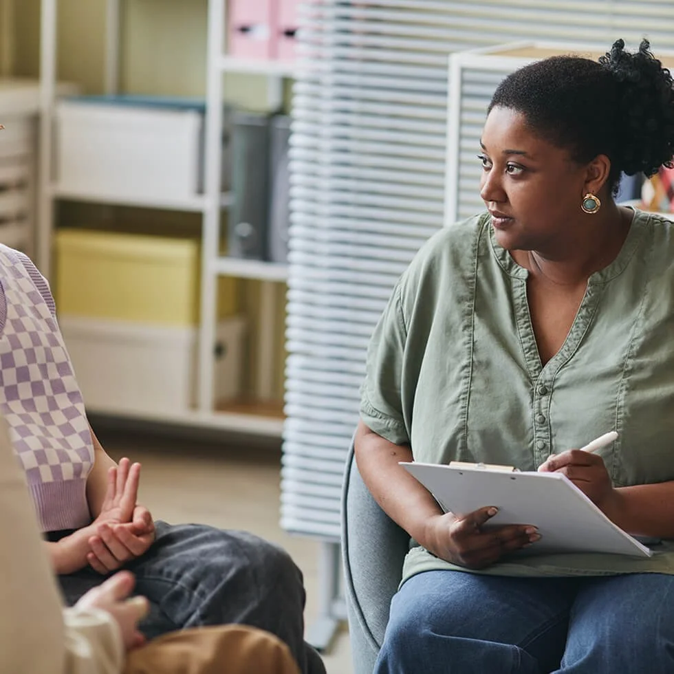 Career counselor speaking with a student while reviewing notes during a career exploration meeting.