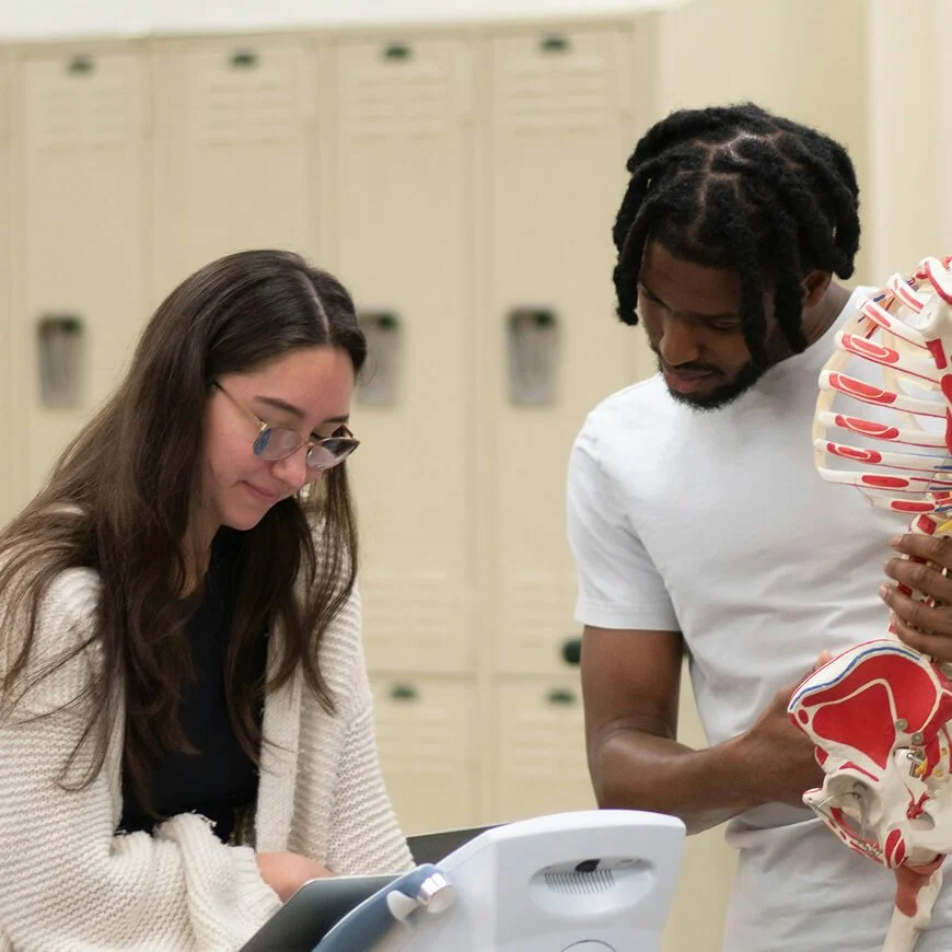 Students reviewing a human anatomy model during a healthcare training activity.