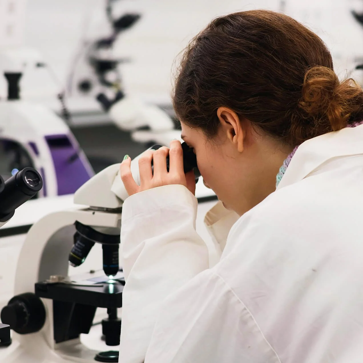Student looking through a microscope in a laboratory setting.