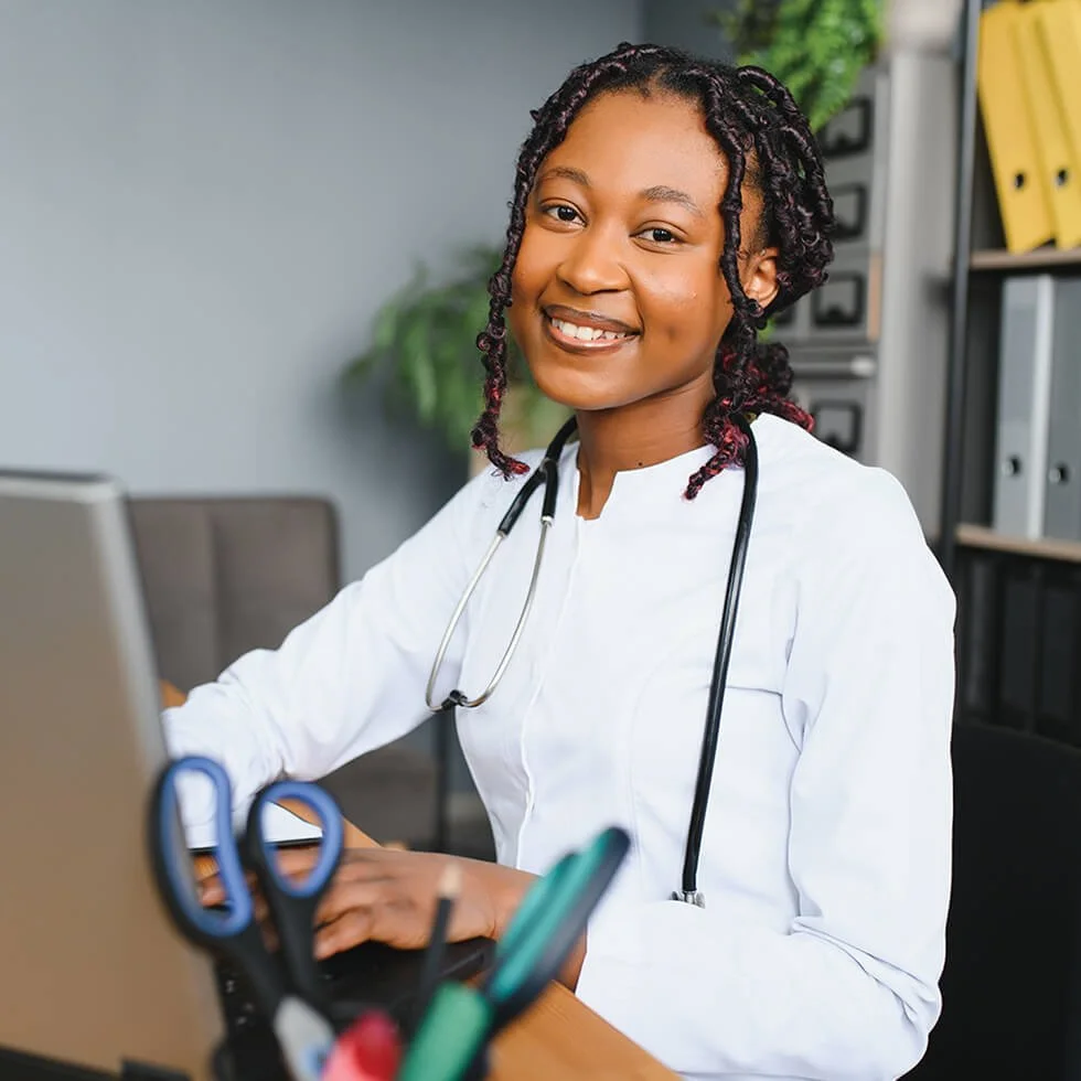 Healthcare professional smiling while working at a desk in a medical office.