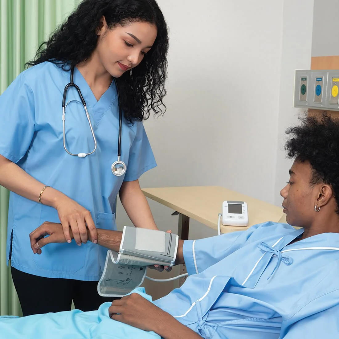 Nurse checking a patient’s blood pressure in a hospital room.