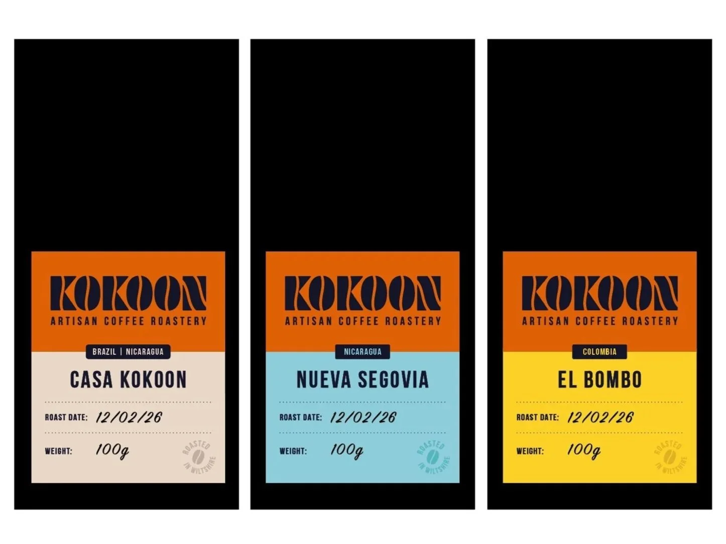 Three bags of Kokoon artisan coffee roastery coffee beans with colorful labels, each indicating different origins and roast dates, standing side by side.