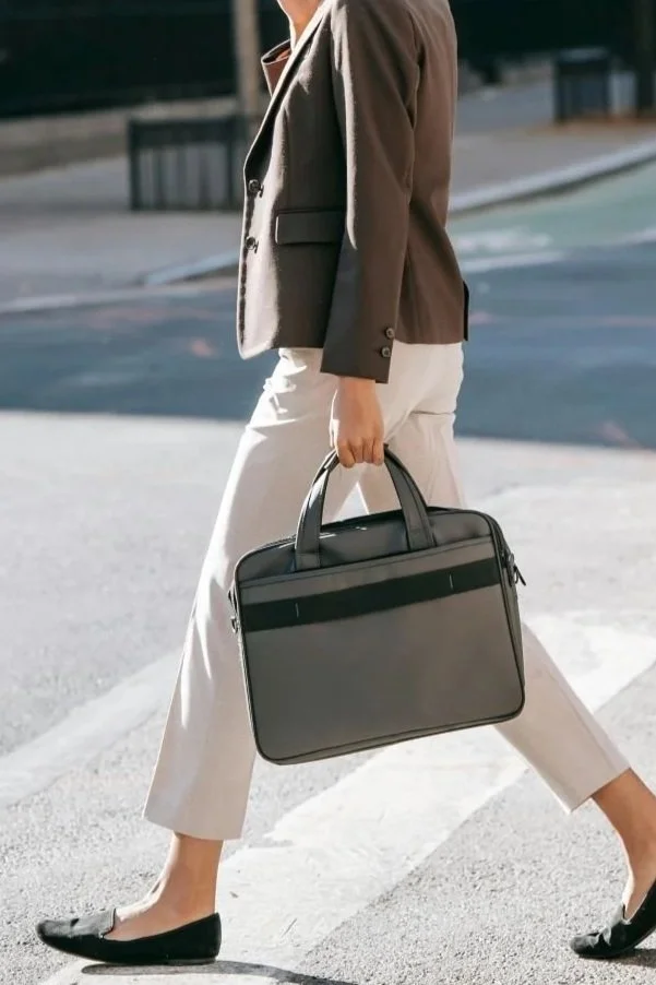 Person in business attire crossing the street, carrying a black briefcase.