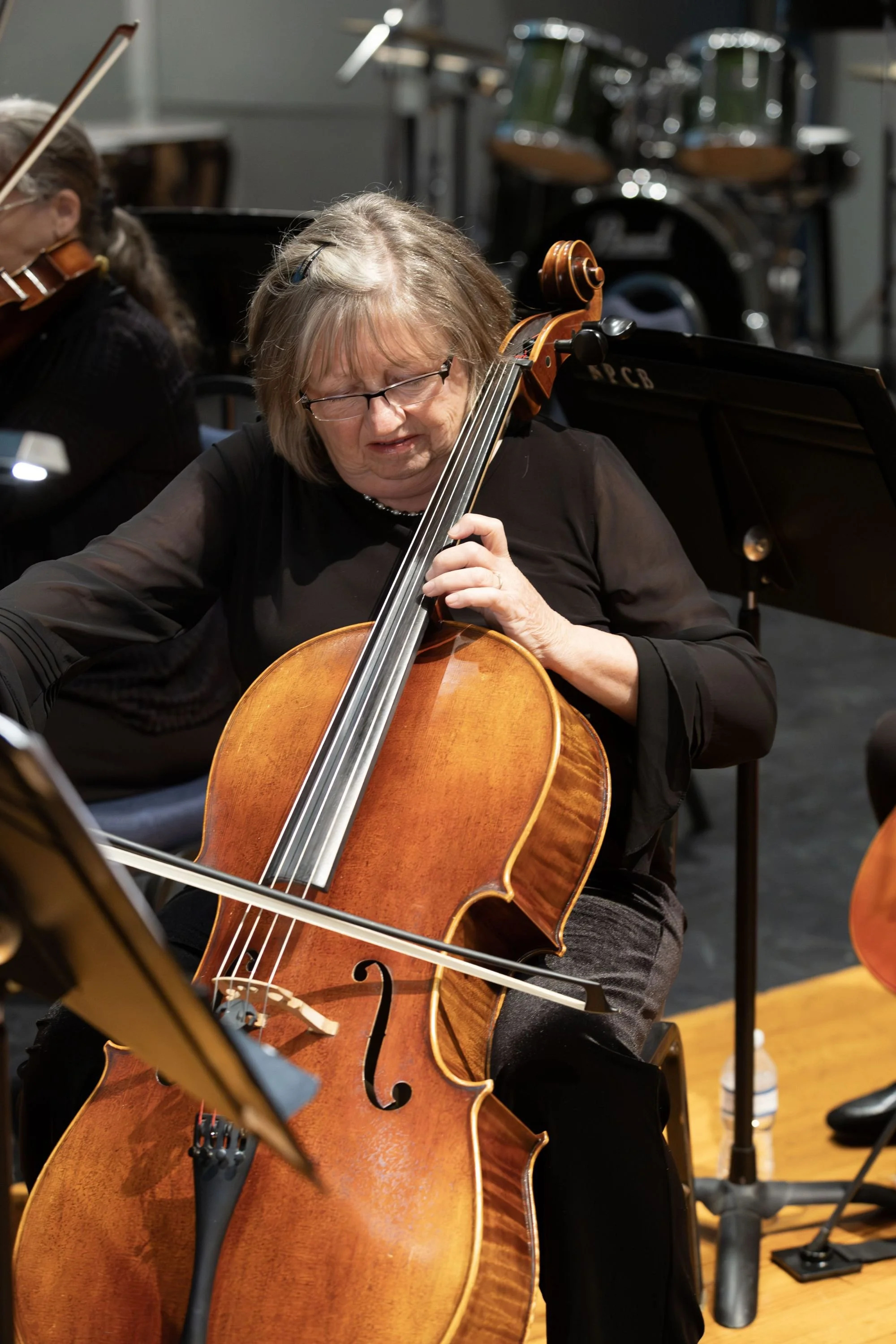 Woman playing a cello during an orchestra rehearsal.
