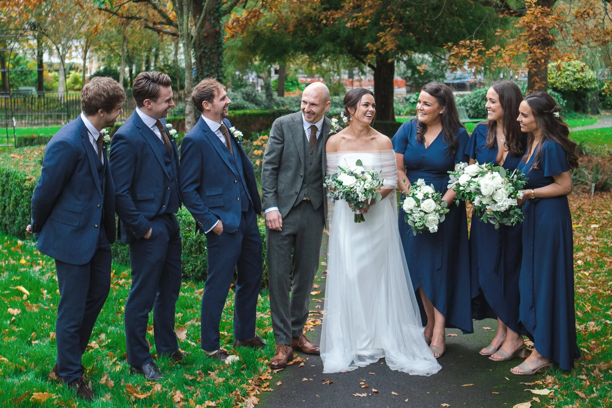 Bridesmaids-and-Groomsmen-with-couple-in-park-having-a-laugh-at-wedding.jpg