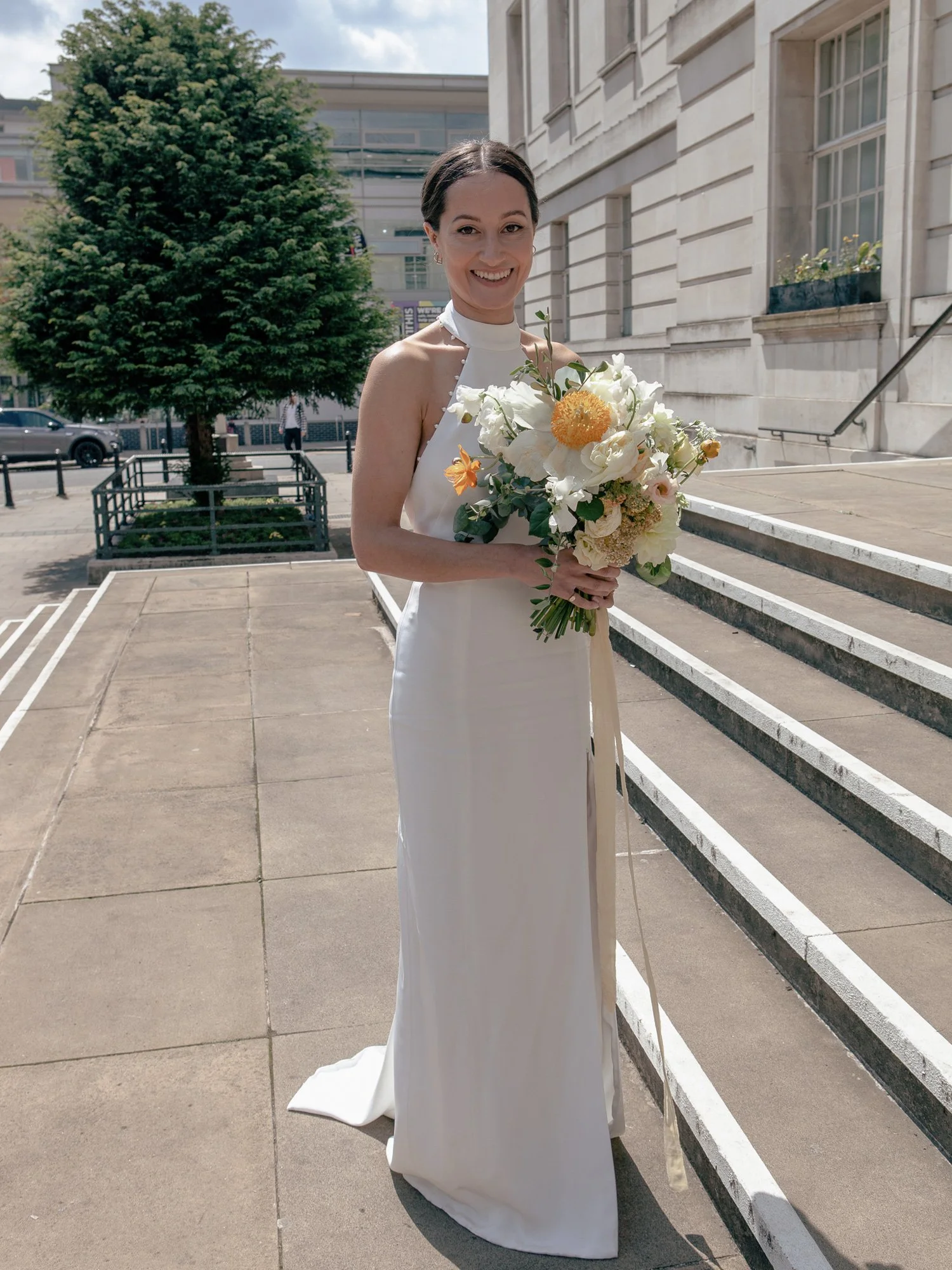 Sunny-bride-poses-on-steps-with-flowers.jpg