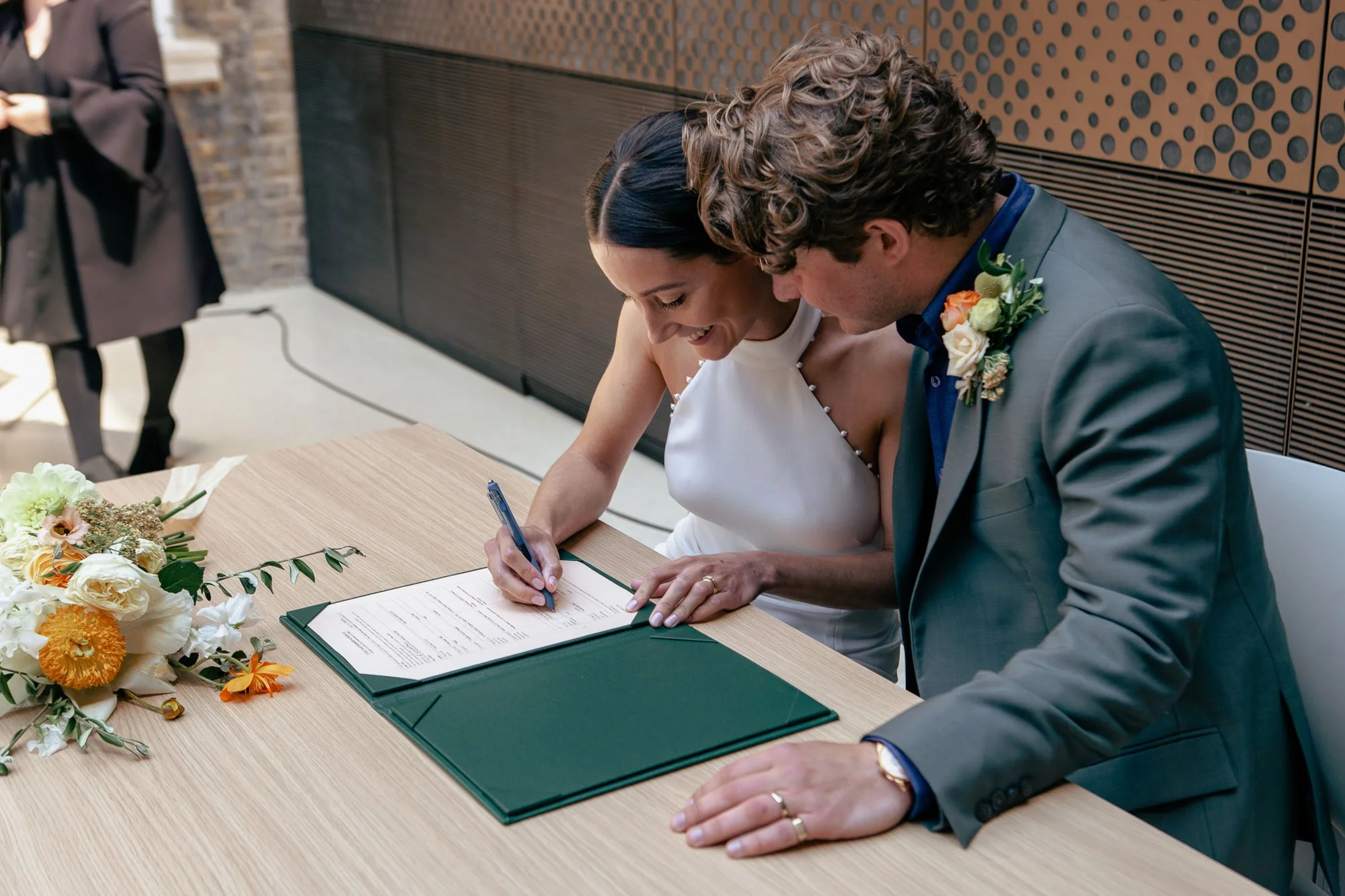 A bride and groom signing a marriage certificate at a wedding ceremony.