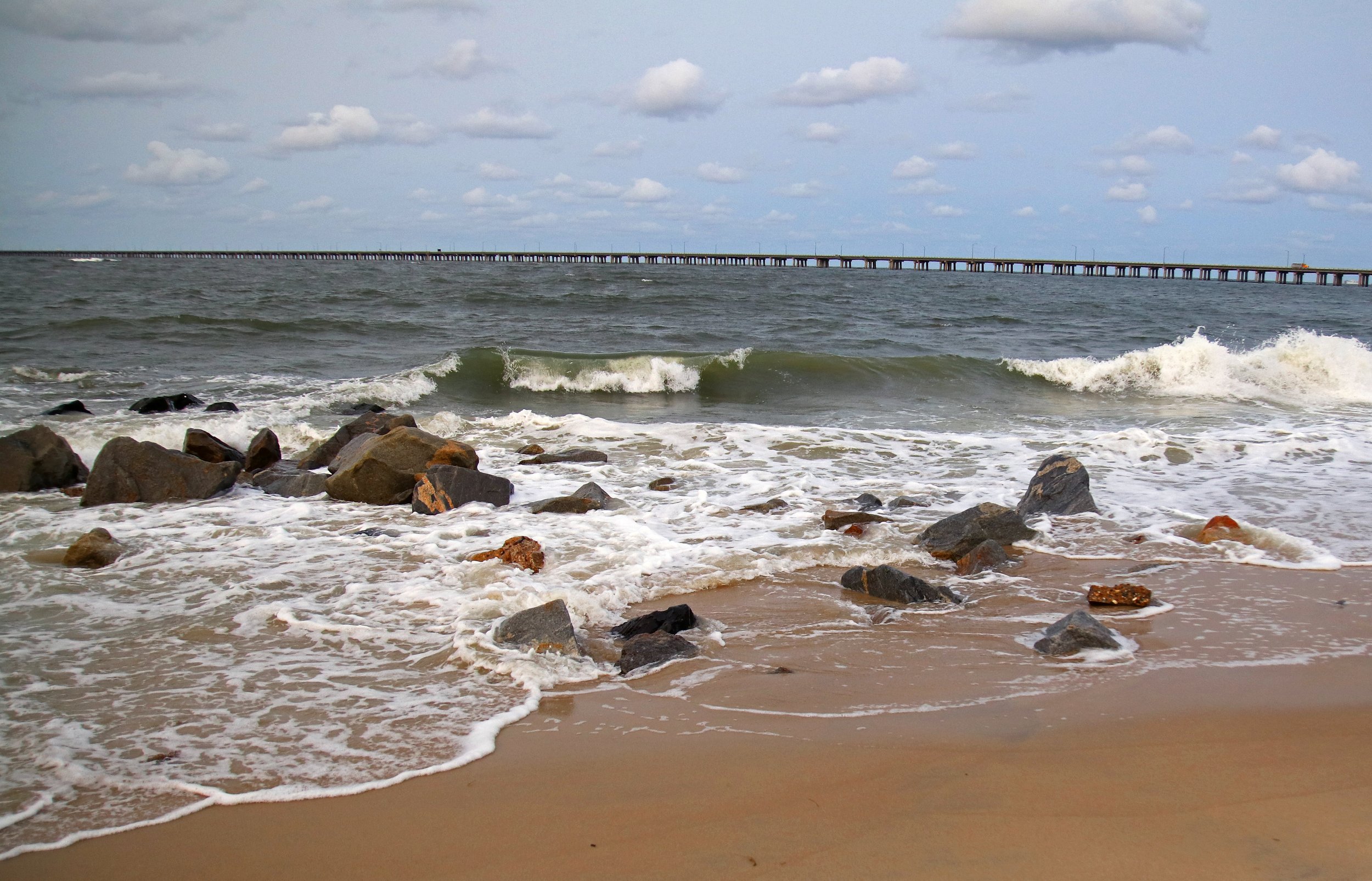 Beach scene, rocks in foreground, Chesapeake Bay Bridge Tunnel in background