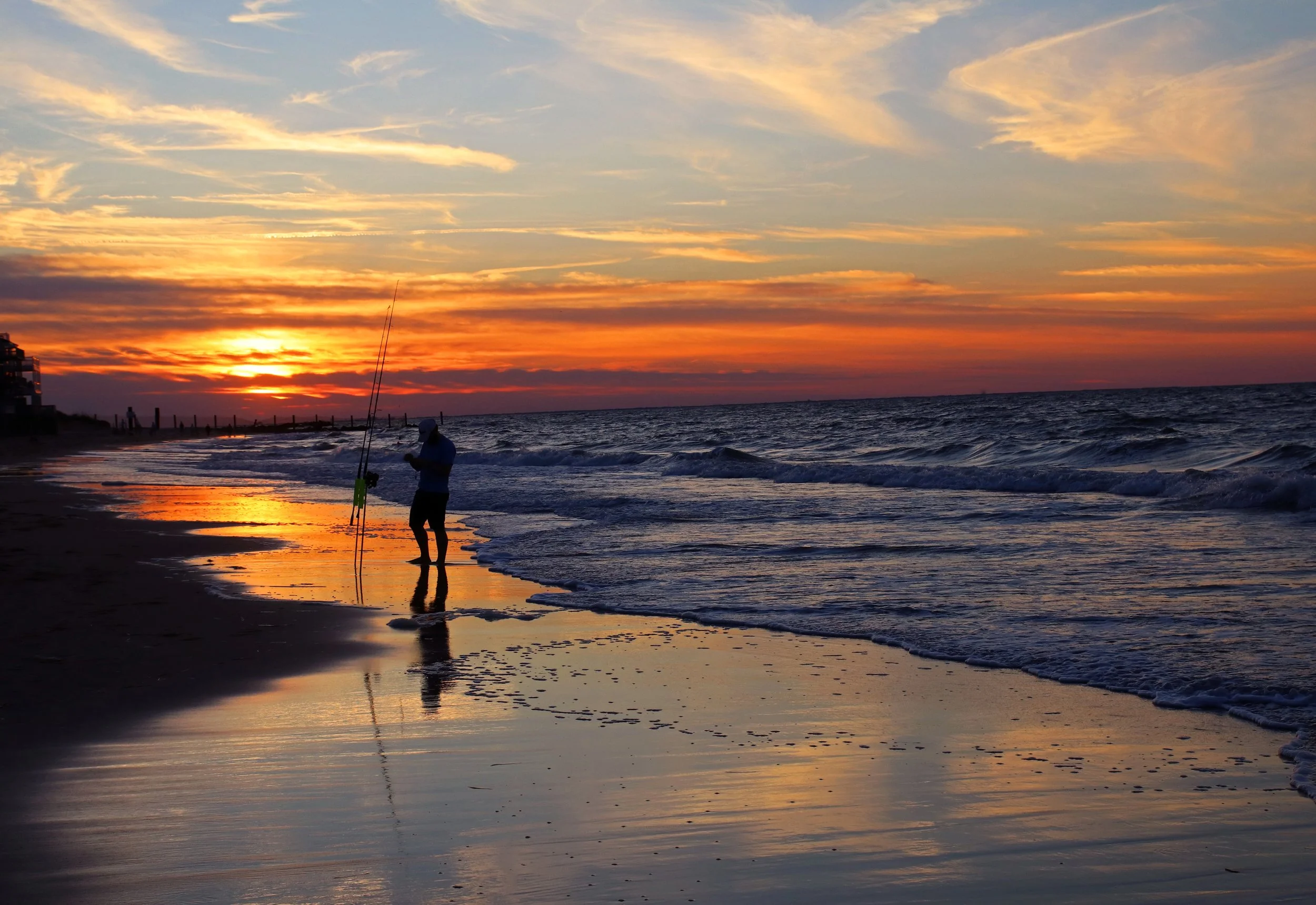 Fisherman silhouette on Chic's beach as sun sets in the background