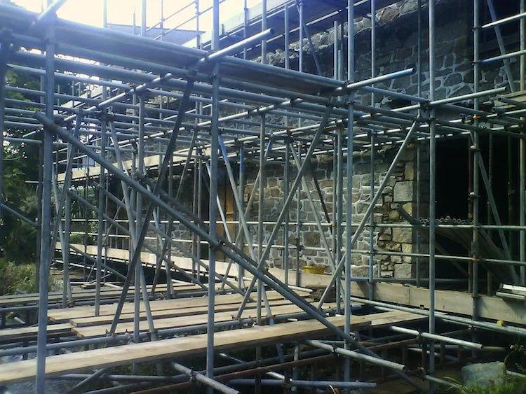 Construction scaffolding around a stone building during renovation.