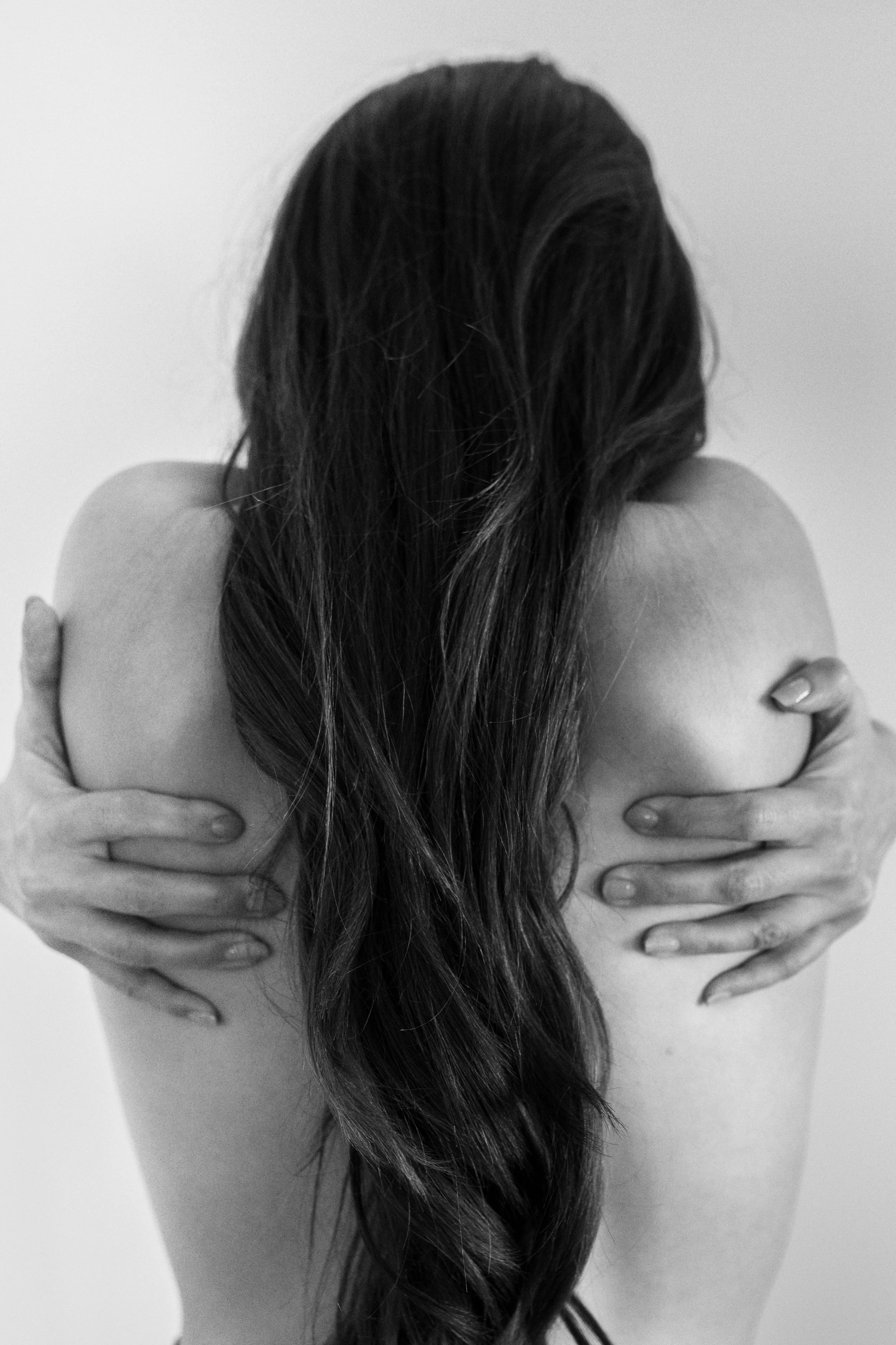 Black and white photo of a woman with long hair hugging herself
