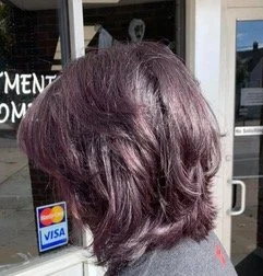 The back of a person's head with purple-brown hair, standing outside a building with a sticker indicating Visa accepted.