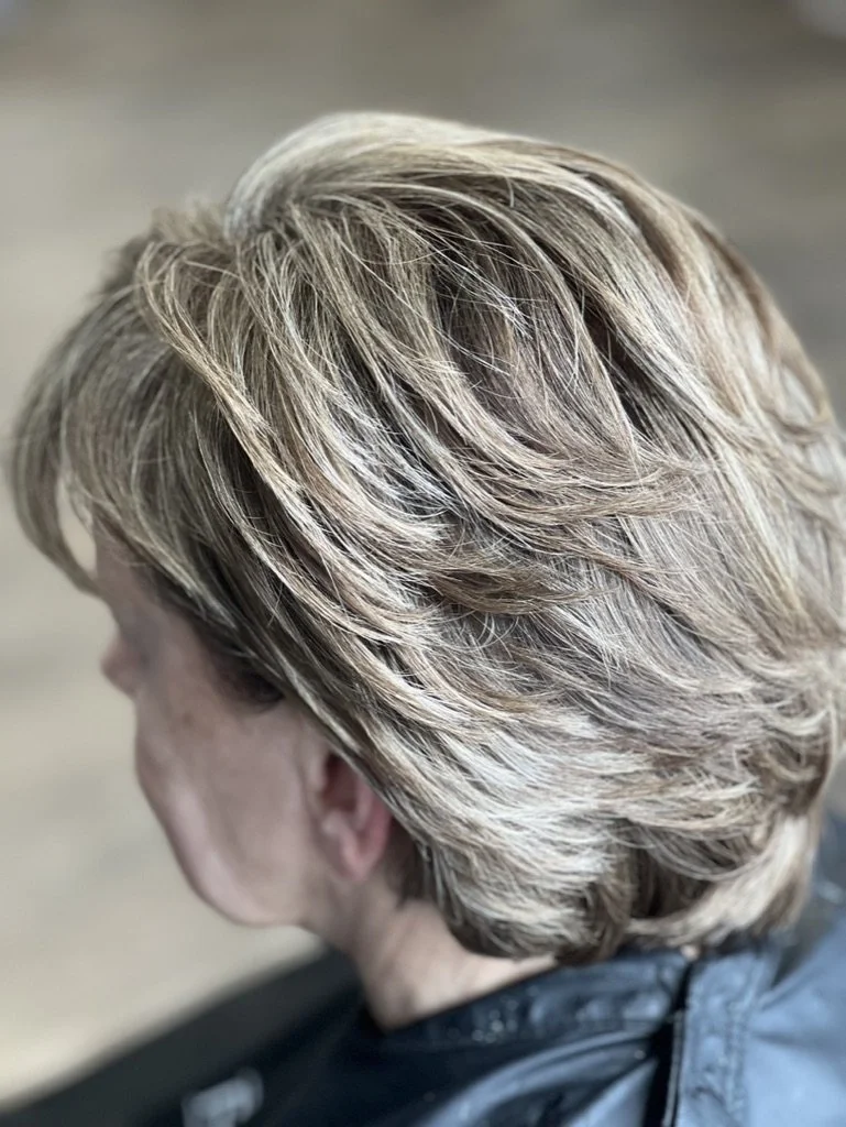 Close-up of a person's short, layered hairstyle with blonde highlights.