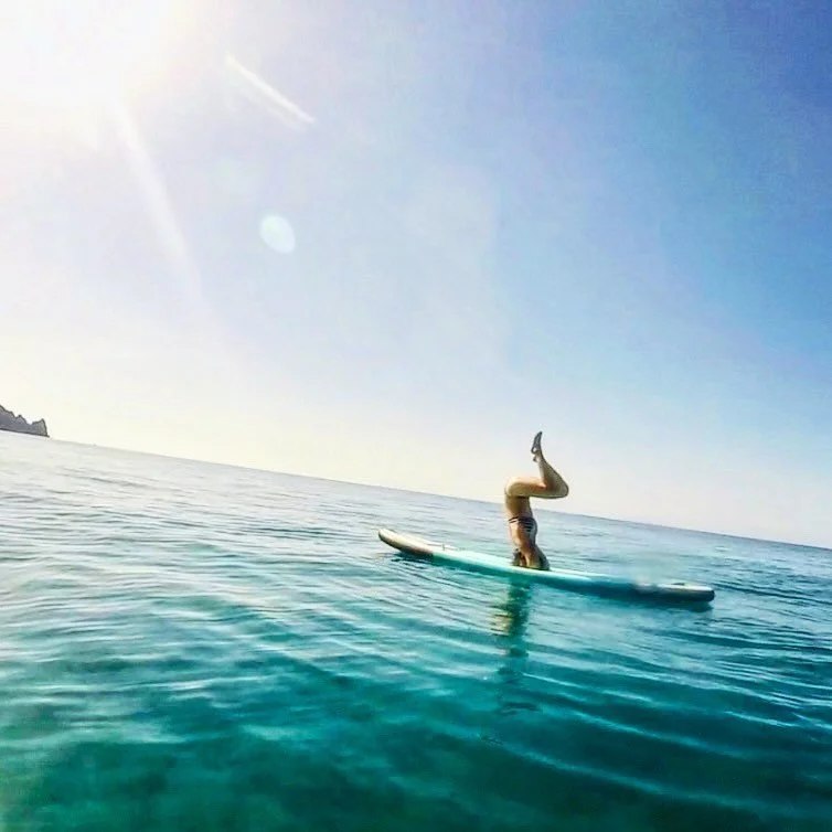 Finding stability in motion. Balancing between the sky and the sea 🌊✨ #SUPYoga #MediterraneanVibes #Headstand #Balance #StandUpPaddeling