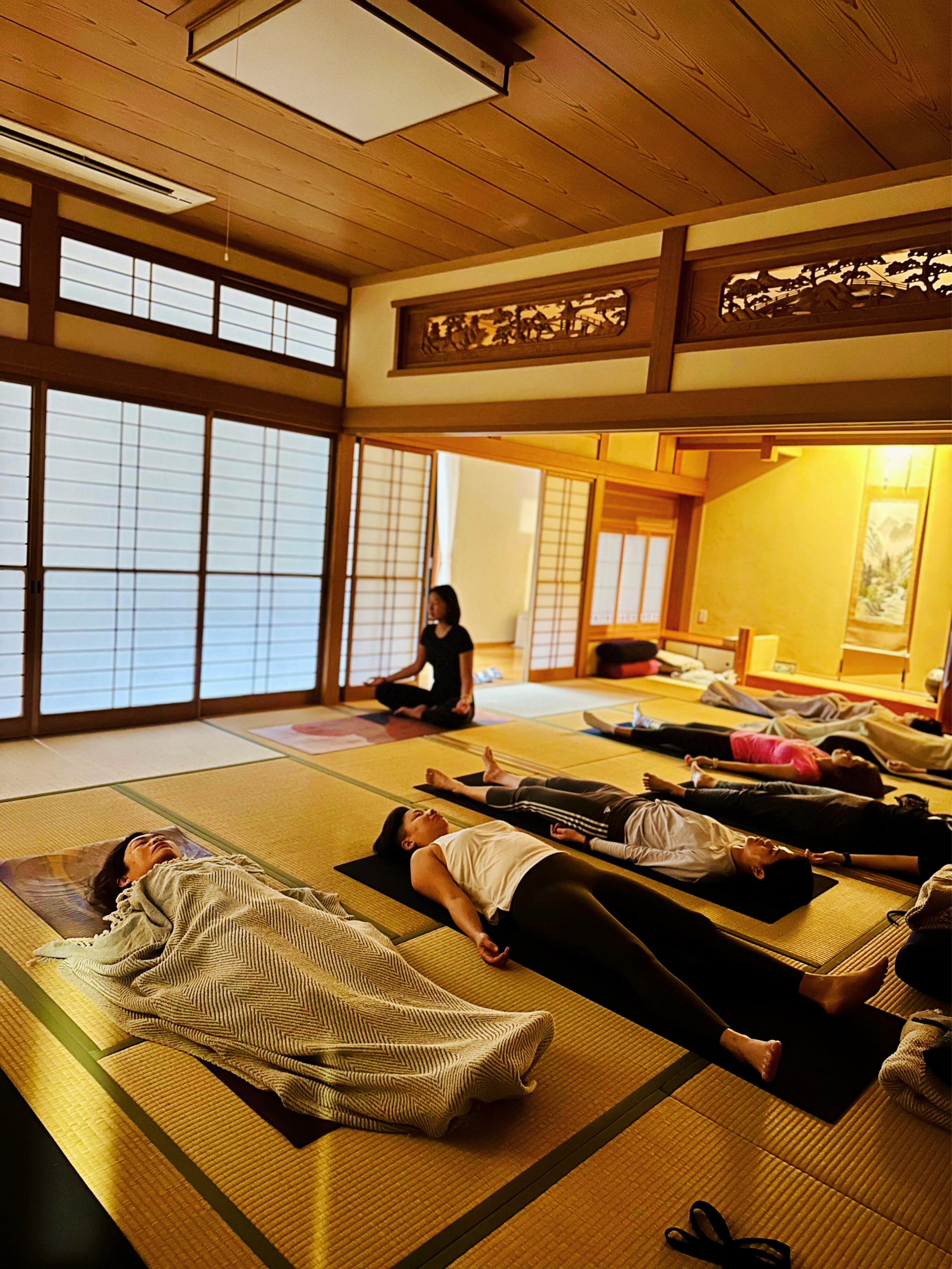 People practicing yoga in a traditional Japanese tatami room during a yoga session.